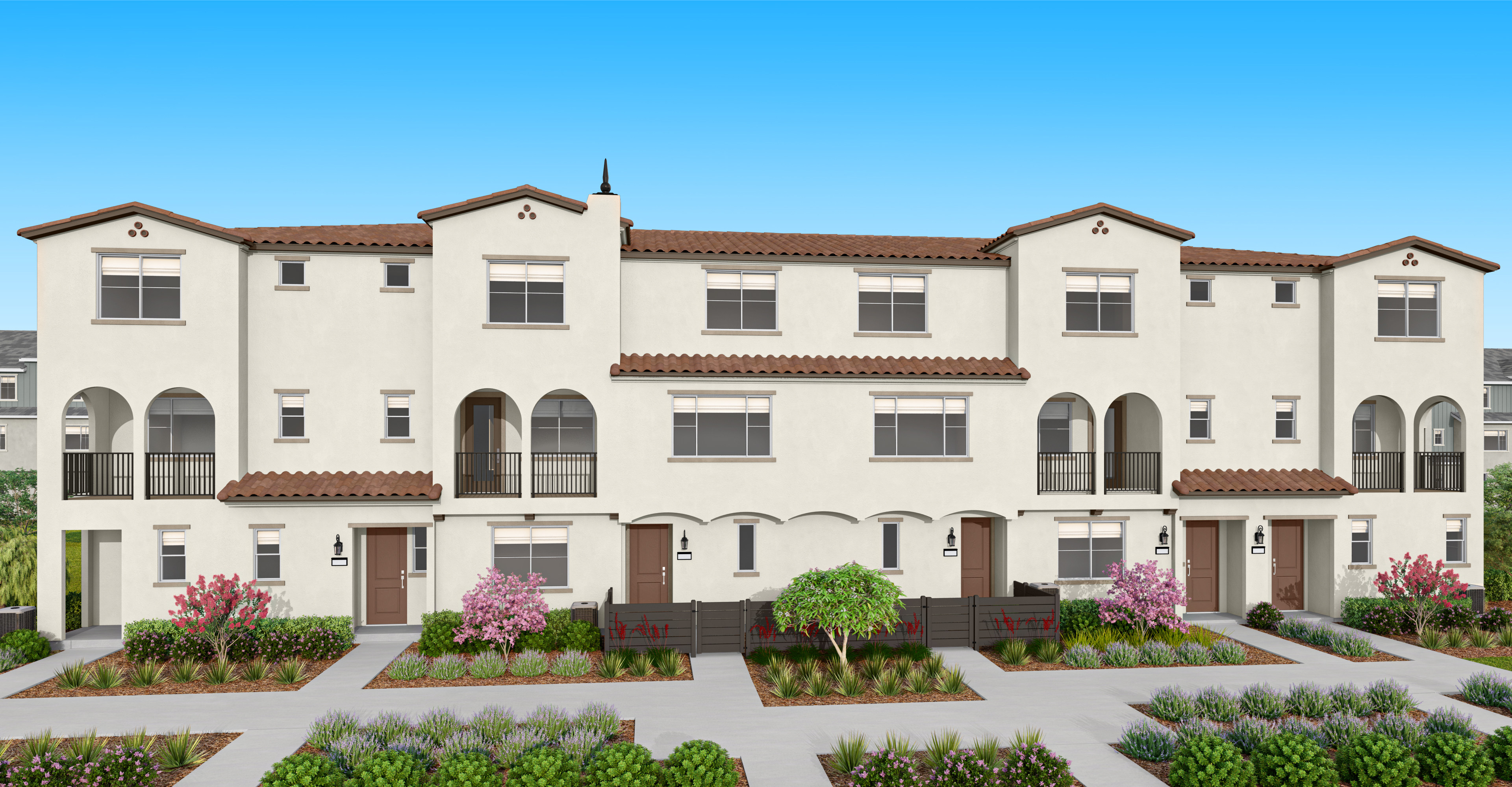 A multi-story residential building with a Spanish-style architecture, surrounded by well-manicured landscaping and a paved walkway in the foreground.