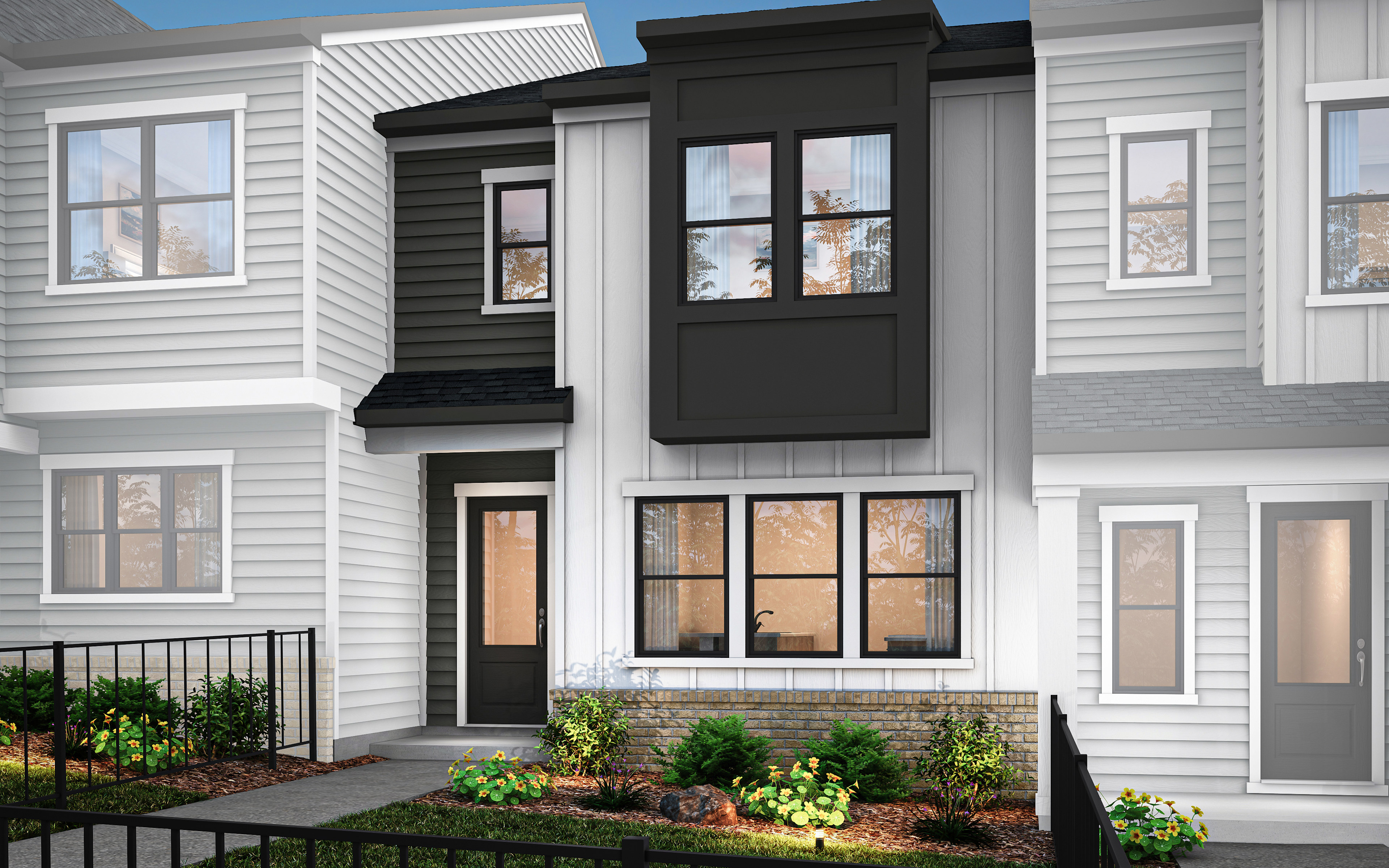 A modern townhouse with a white exterior, black trim, and a well-landscaped front yard featuring greenery and plants.