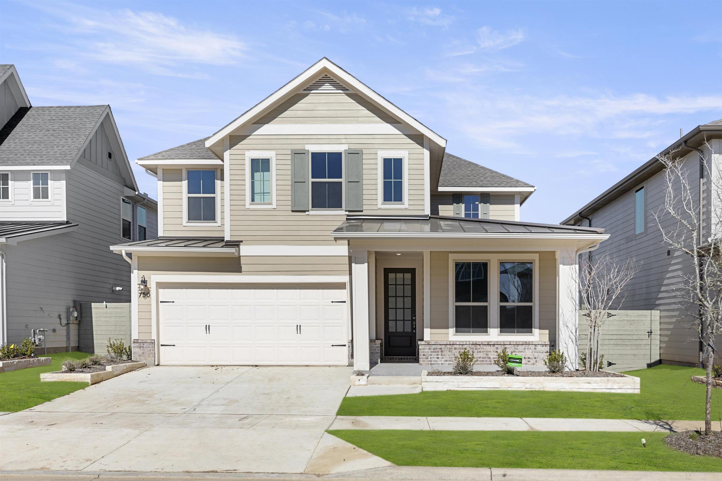 A two-story residential house with a garage, surrounded by a well-manicured lawn and other houses in the background.