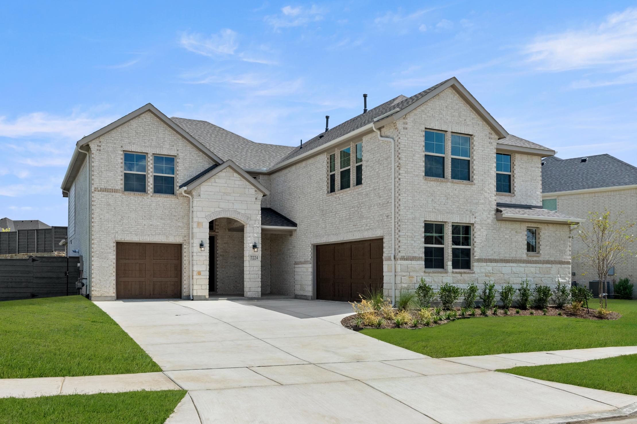 A two-story residential house with a gray exterior, a tiled roof, and a well-manicured lawn in the foreground.