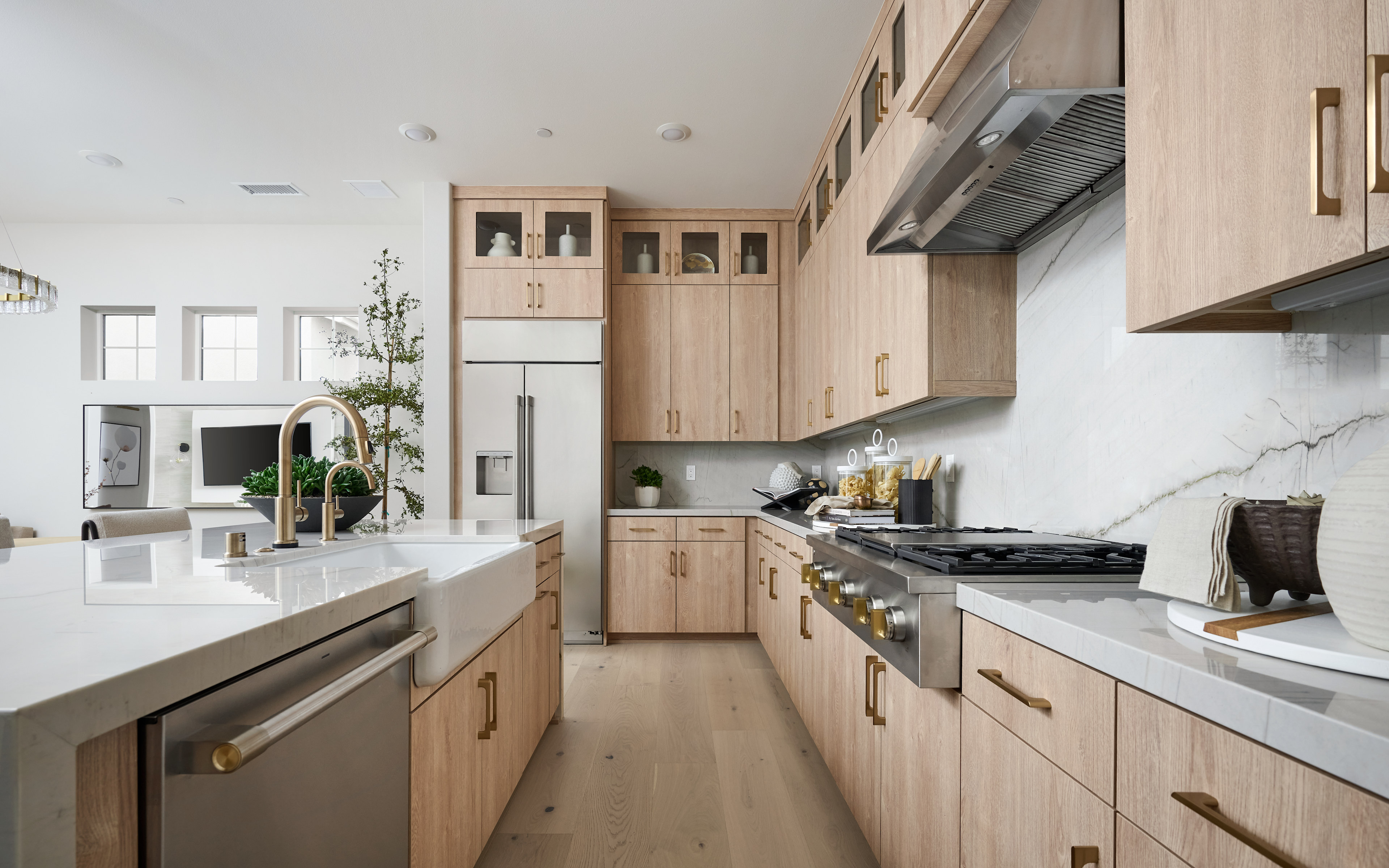 A modern, minimalist kitchen with light wood cabinetry, stainless steel appliances, and a marble countertop, creating a sleek and stylish atmosphere.