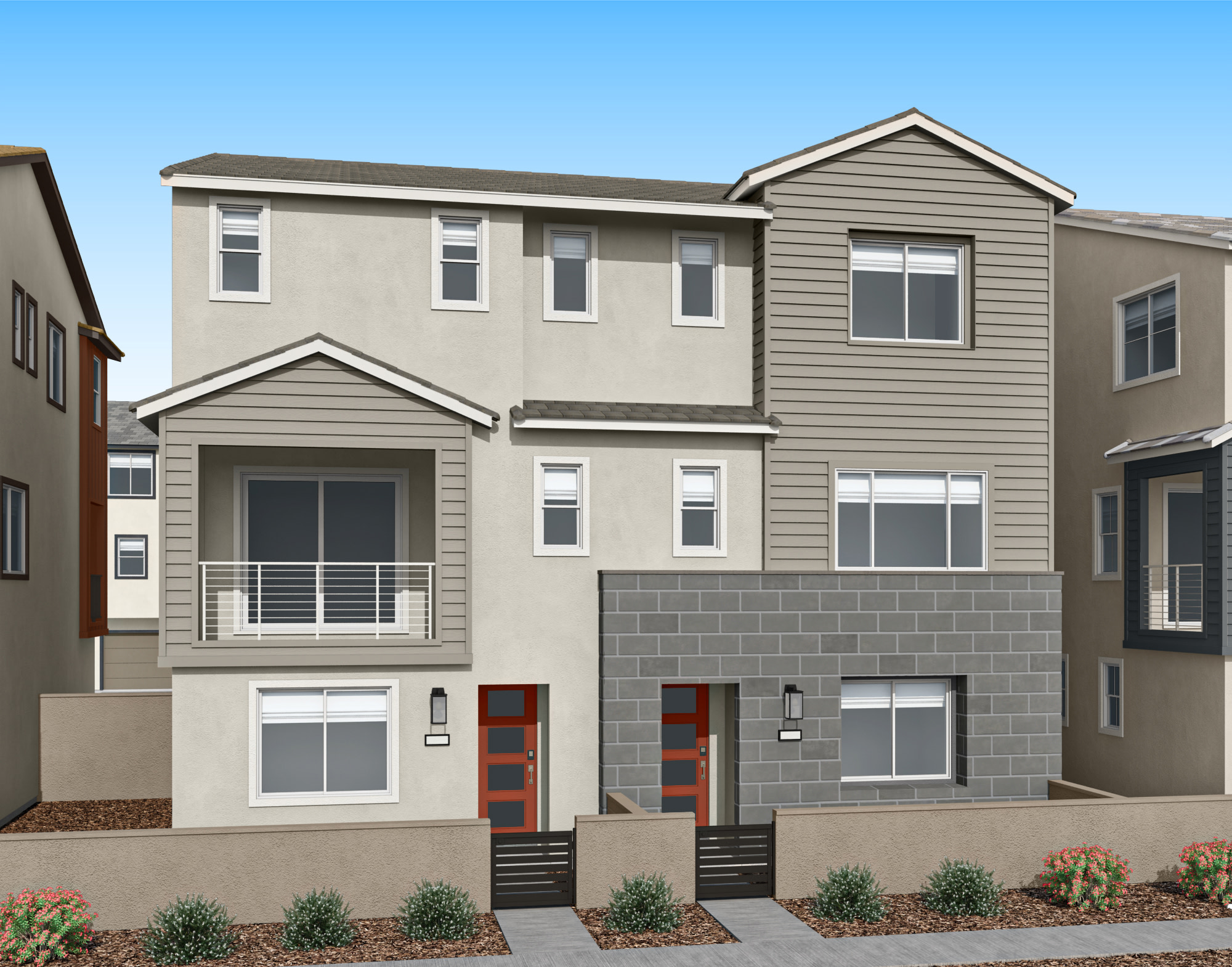 A multi-story residential building with a gray exterior, featuring a balcony and landscaped front yard against a clear blue sky.