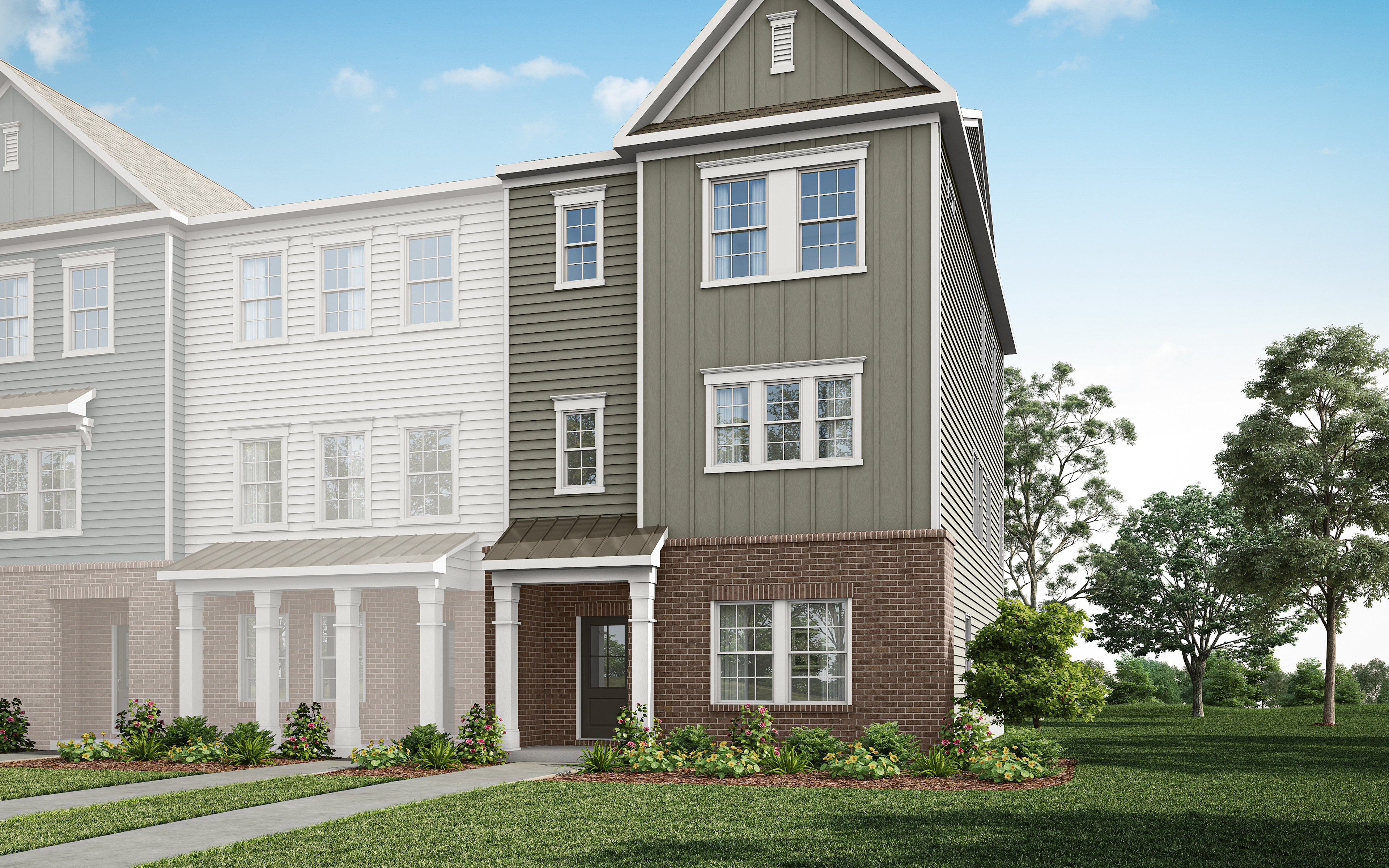 A multi-story townhouse with a gray exterior, white trim, and a brick foundation sits in a grassy area with trees in the background.