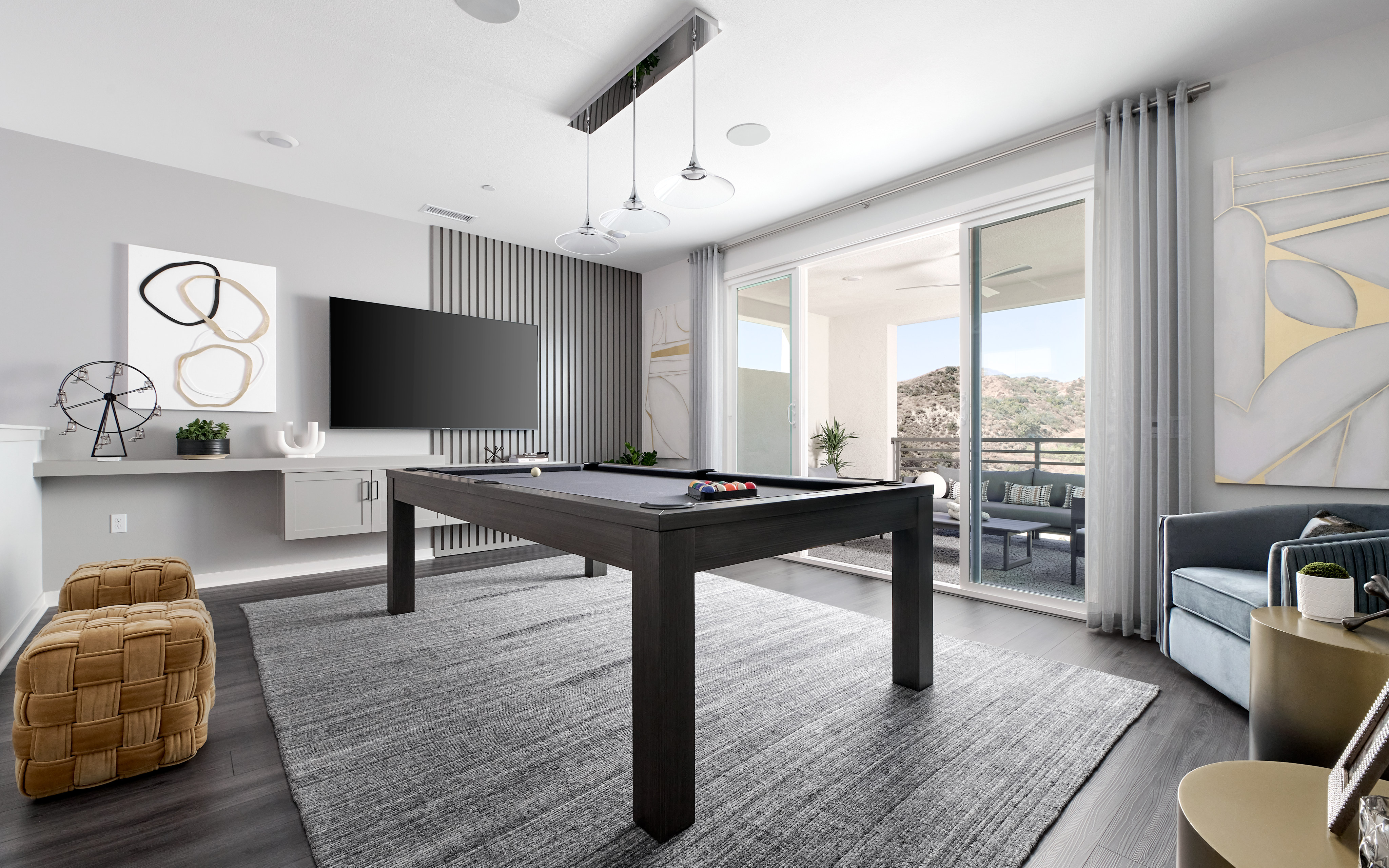 A modern and stylish living room with a pool table, large windows, and various decorative elements.
