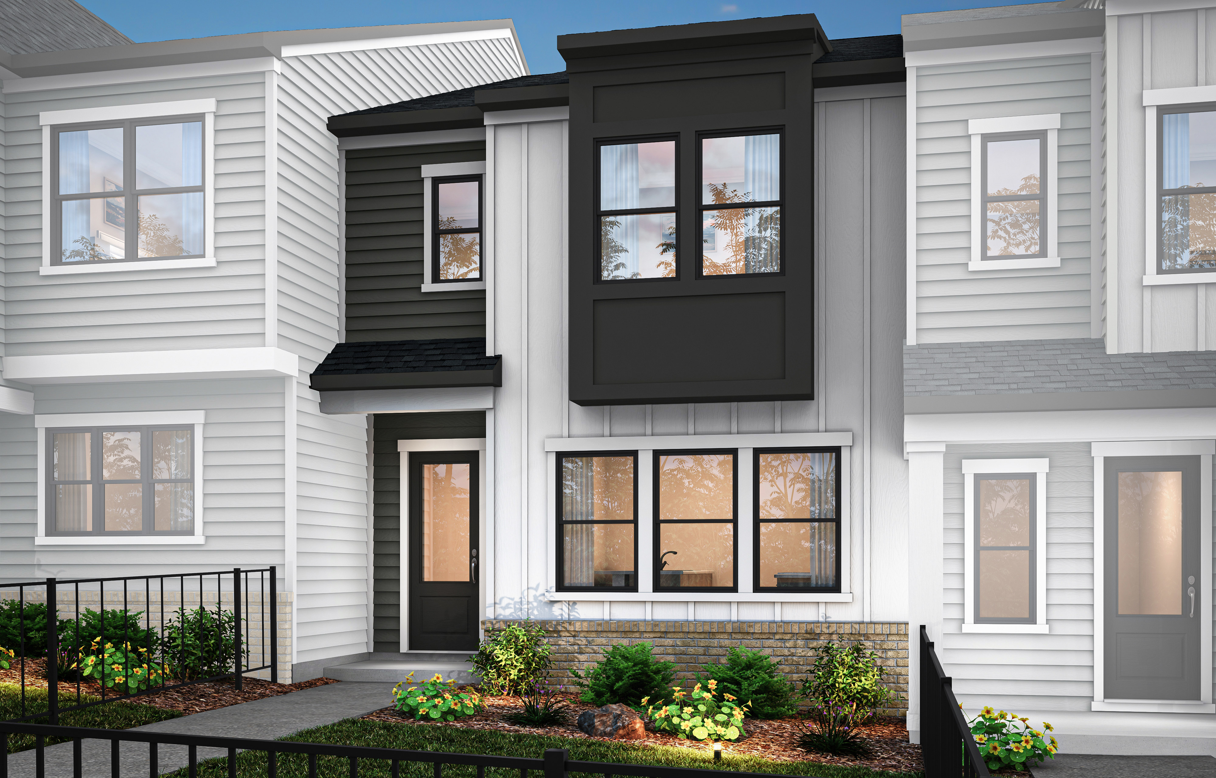 A modern townhouse with a white exterior, black trim, and a well-landscaped front yard featuring greenery and plants.