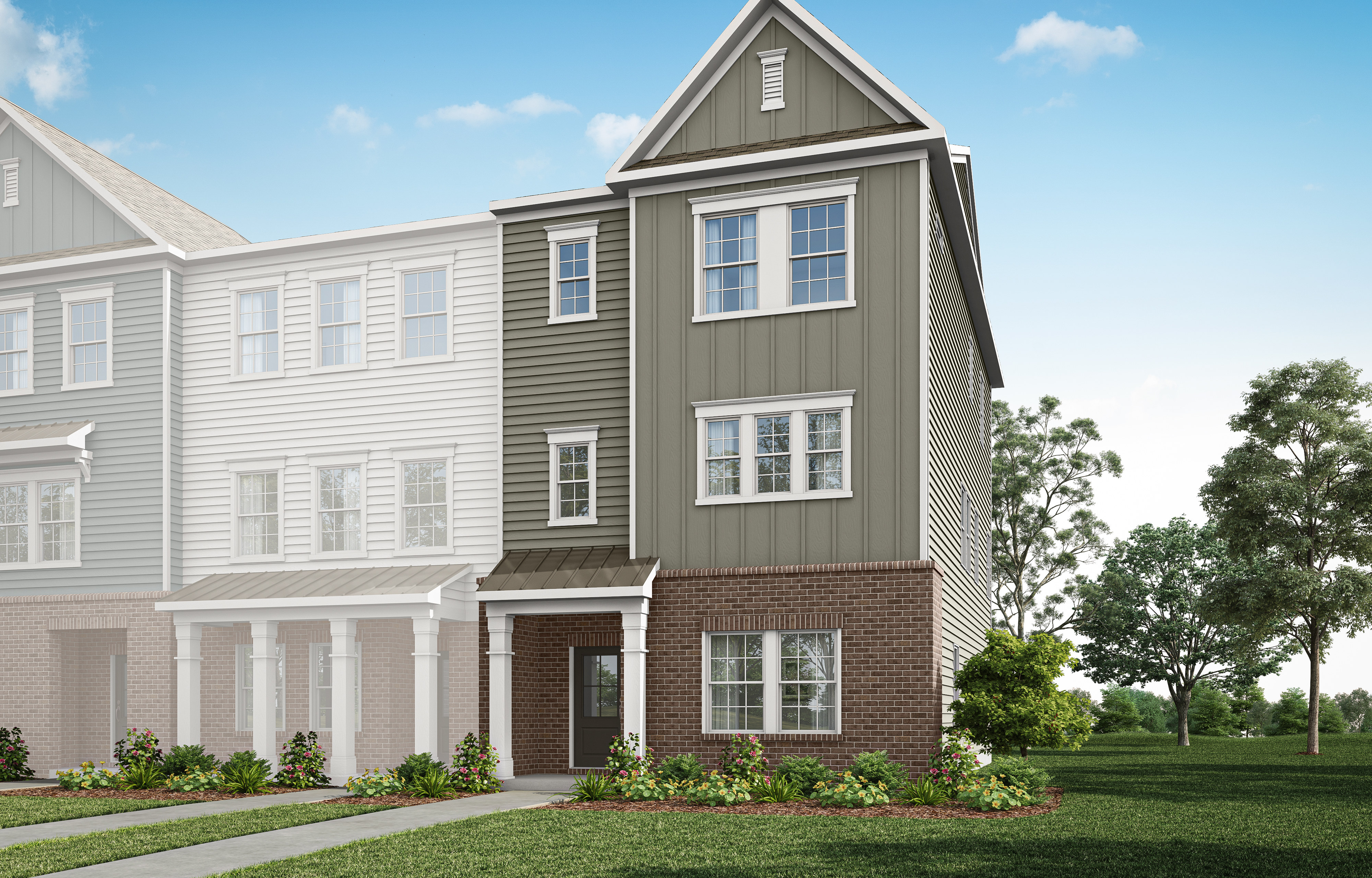A multi-story townhouse with a gray exterior, white trim, and a brick foundation sits in a grassy area with trees in the background.