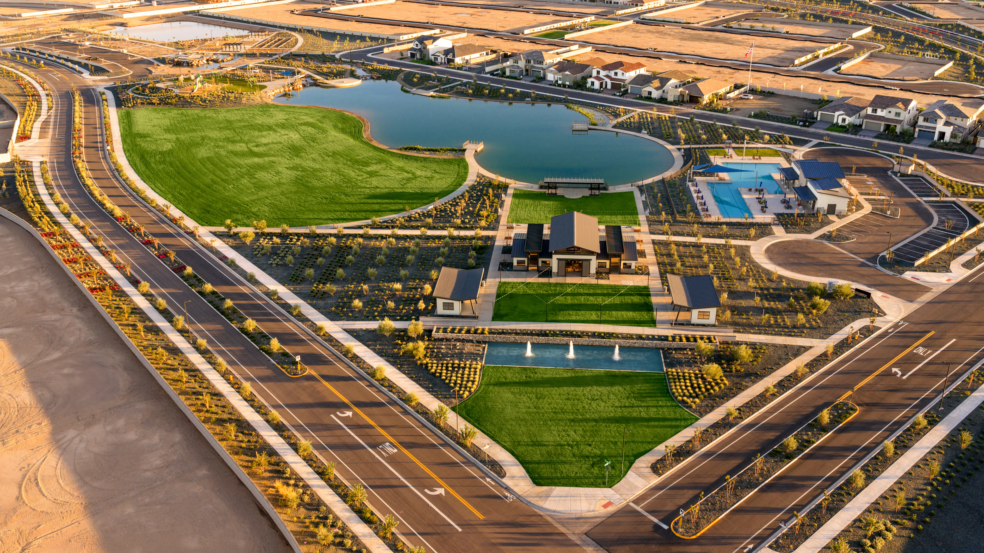 An aerial view of a sprawling urban development with a network of roads, buildings, and landscaped green spaces surrounding a series of artificial lakes or ponds.