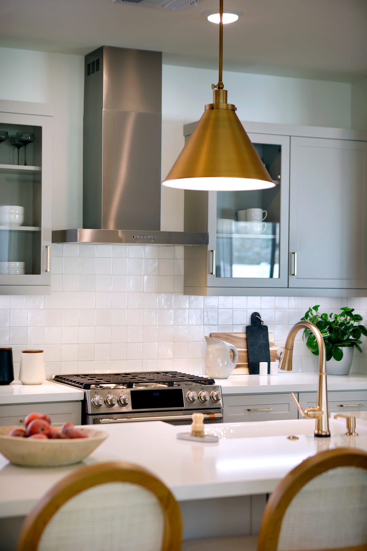 A modern, well-equipped kitchen with a large stove, a golden pendant light, and a countertop with various kitchen items.