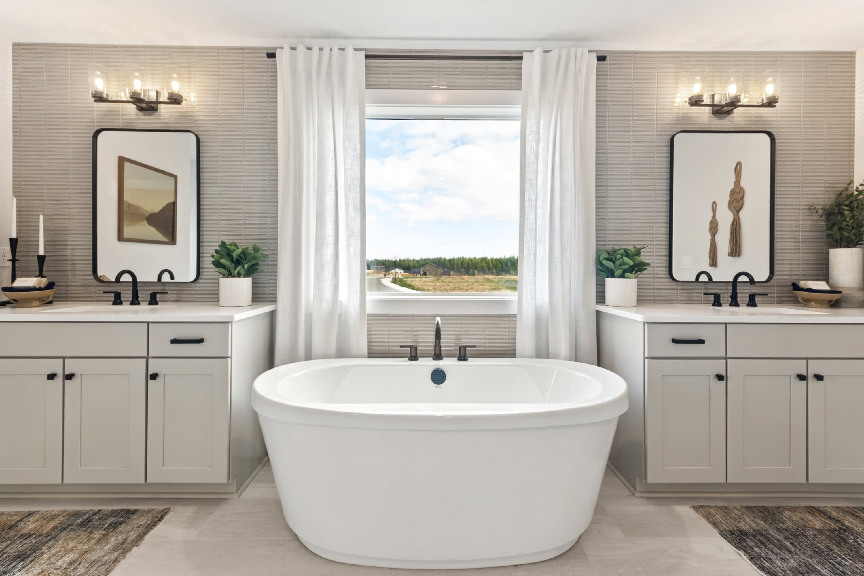 A spacious and well-designed bathroom with a freestanding bathtub, double vanity, and large window overlooking a scenic outdoor landscape.