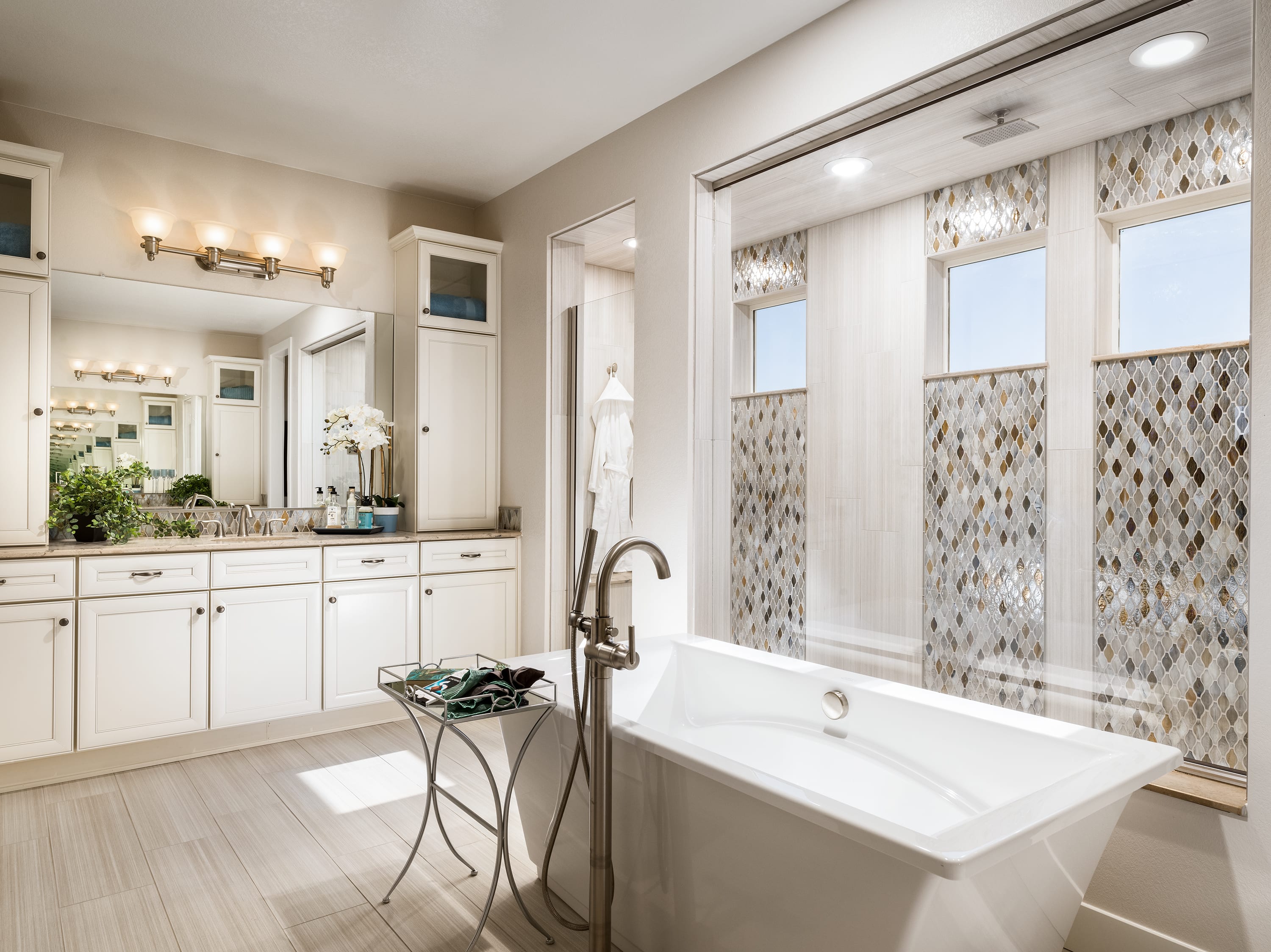 A spacious and well-designed bathroom with a freestanding bathtub, vanity with double sinks, and decorative tile accents on the walls.