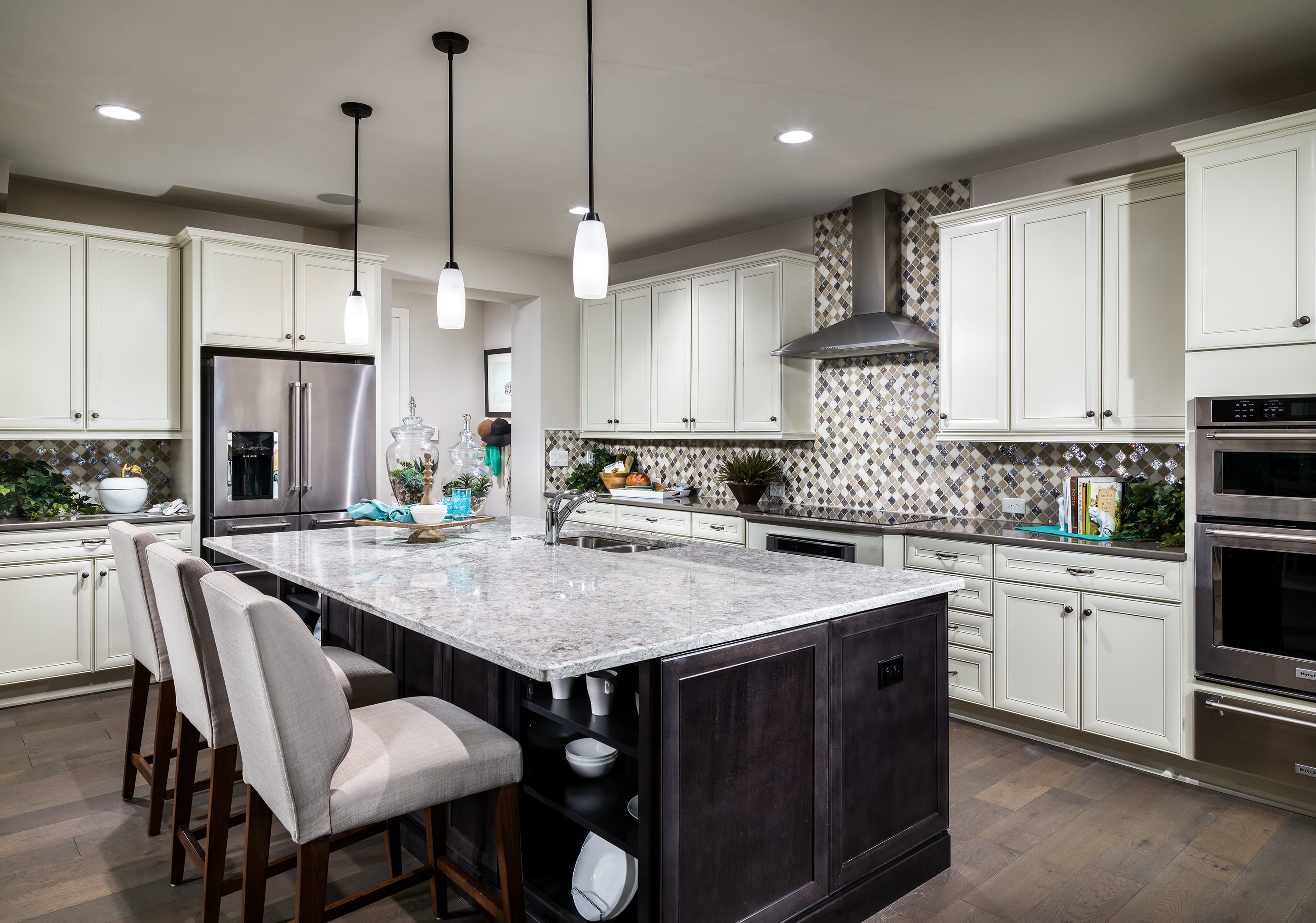 A modern and well-designed kitchen with white cabinets, a large island with a marble countertop, and pendant lighting fixtures.