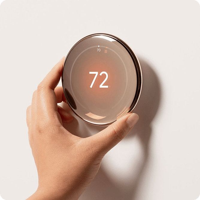 A hand adjusting a thermostat that reads 72