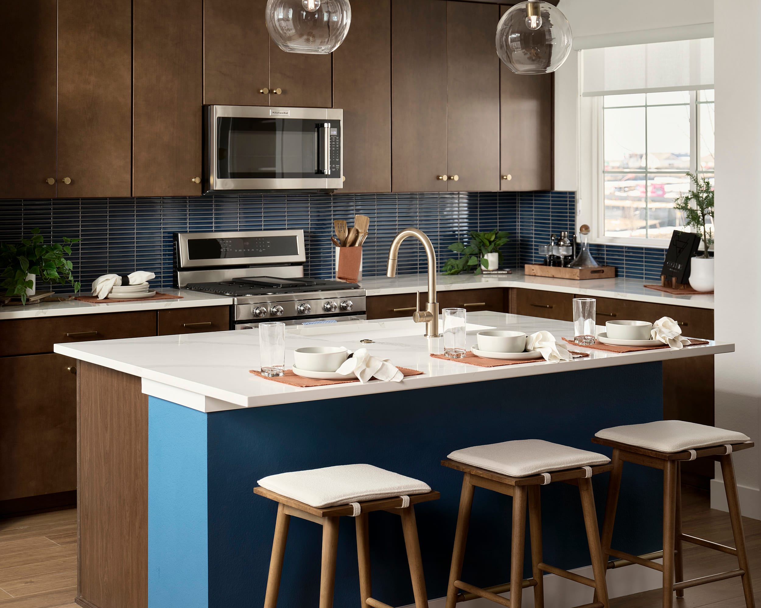 A modern and stylish kitchen with a blue island, wooden cabinets, and a tiled backsplash, featuring various kitchen appliances and decor.