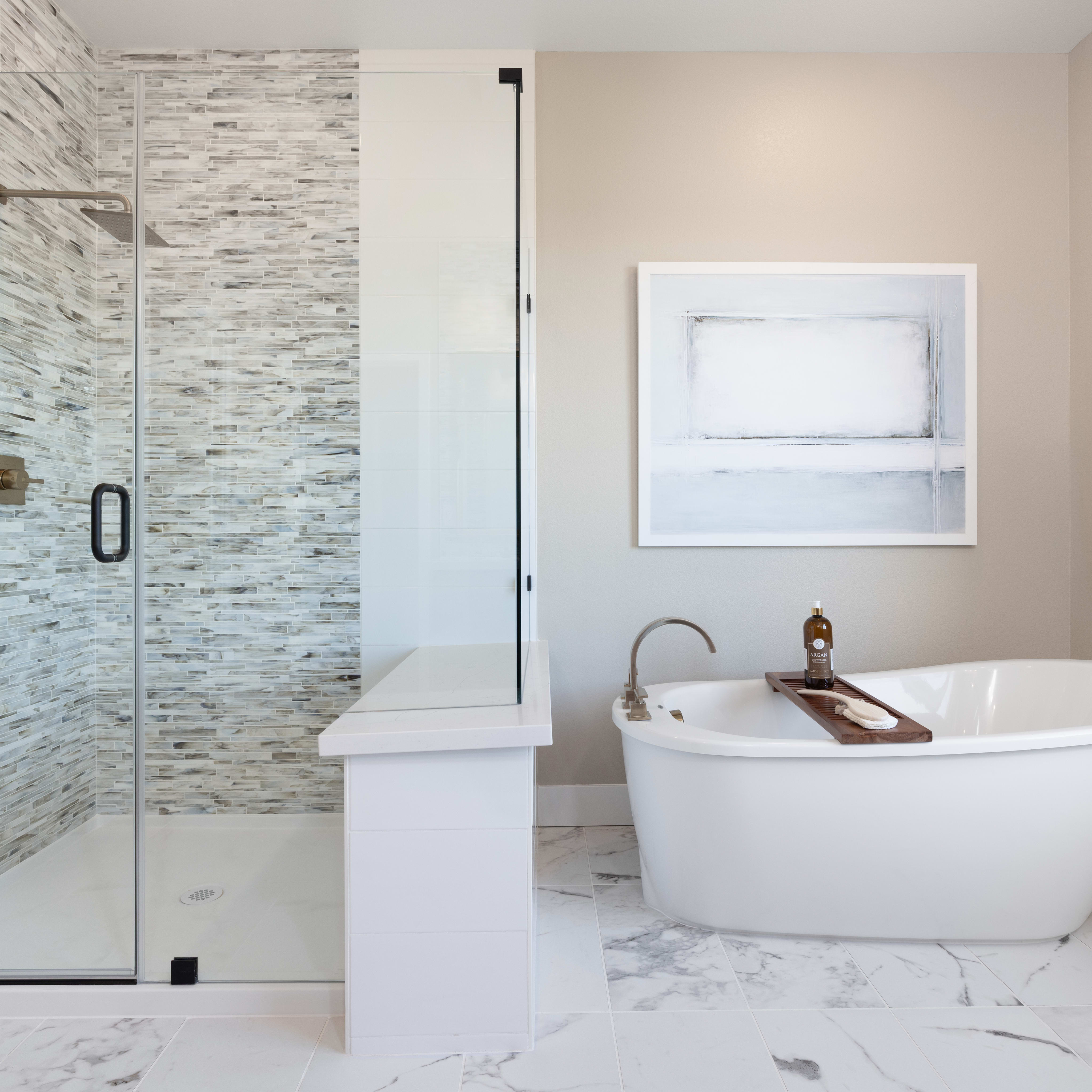 A modern and elegant bathroom with a freestanding bathtub, a glass-enclosed shower, and a marble-tiled floor.