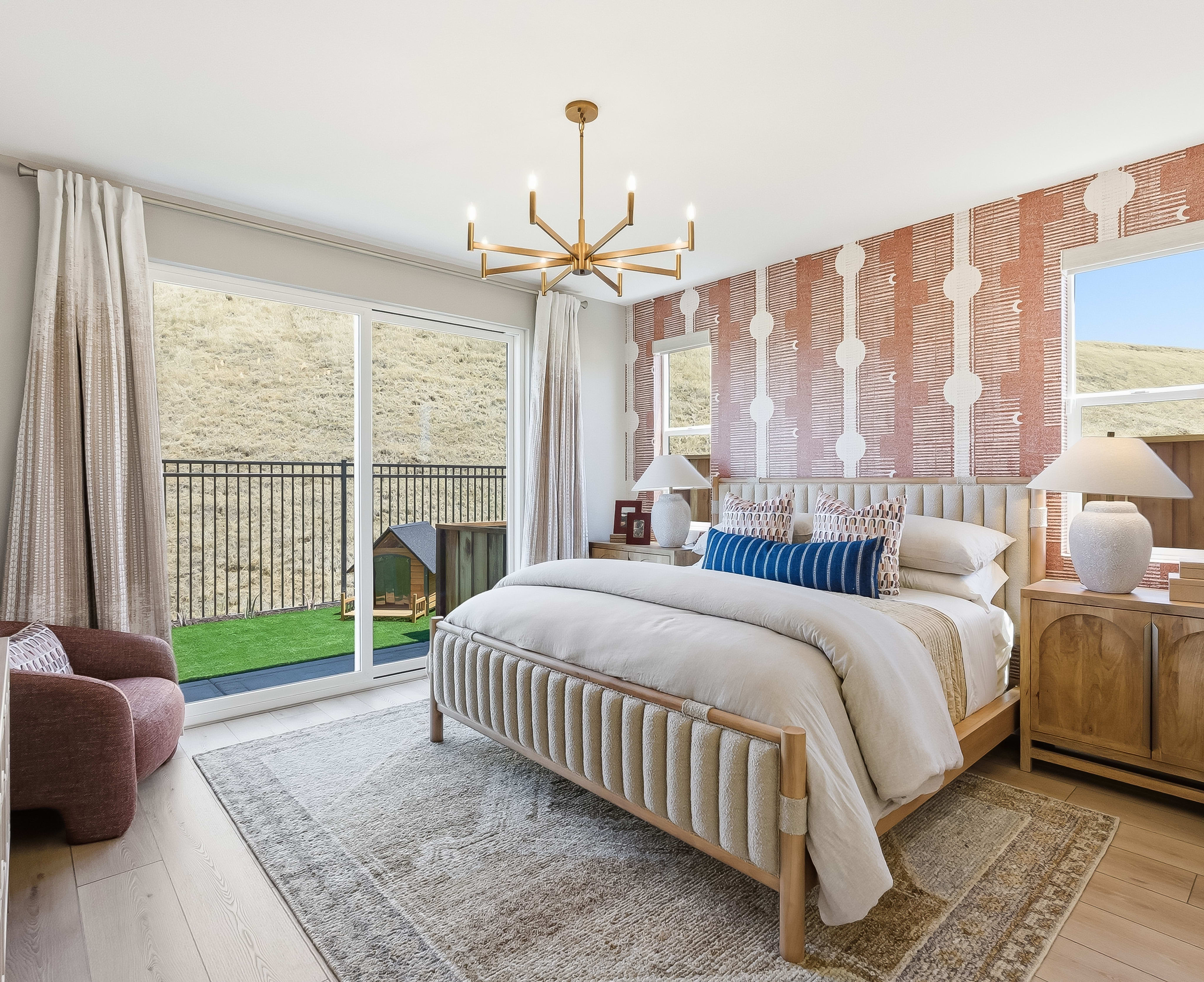 A plush bedroom with a king-sized bed and patterned wallpaper opens to a backyard with a doghouse and rolling hills.