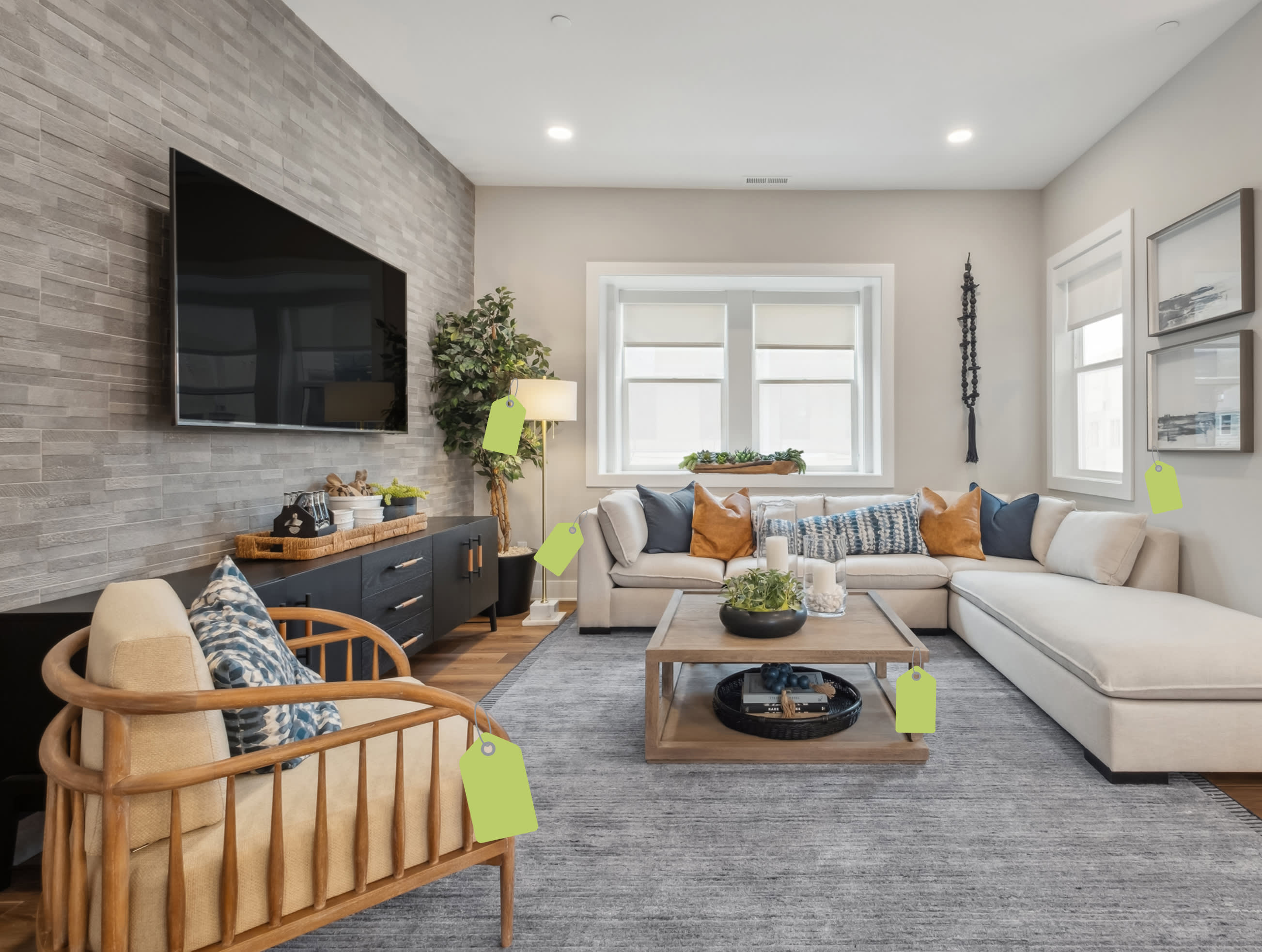 A wooden armchair with a blue patterned pillow sits in the foreground of a modern living room featuring a large sectional sofa, a coffee table, and a wall-mounted TV against a textured grey accent wall.