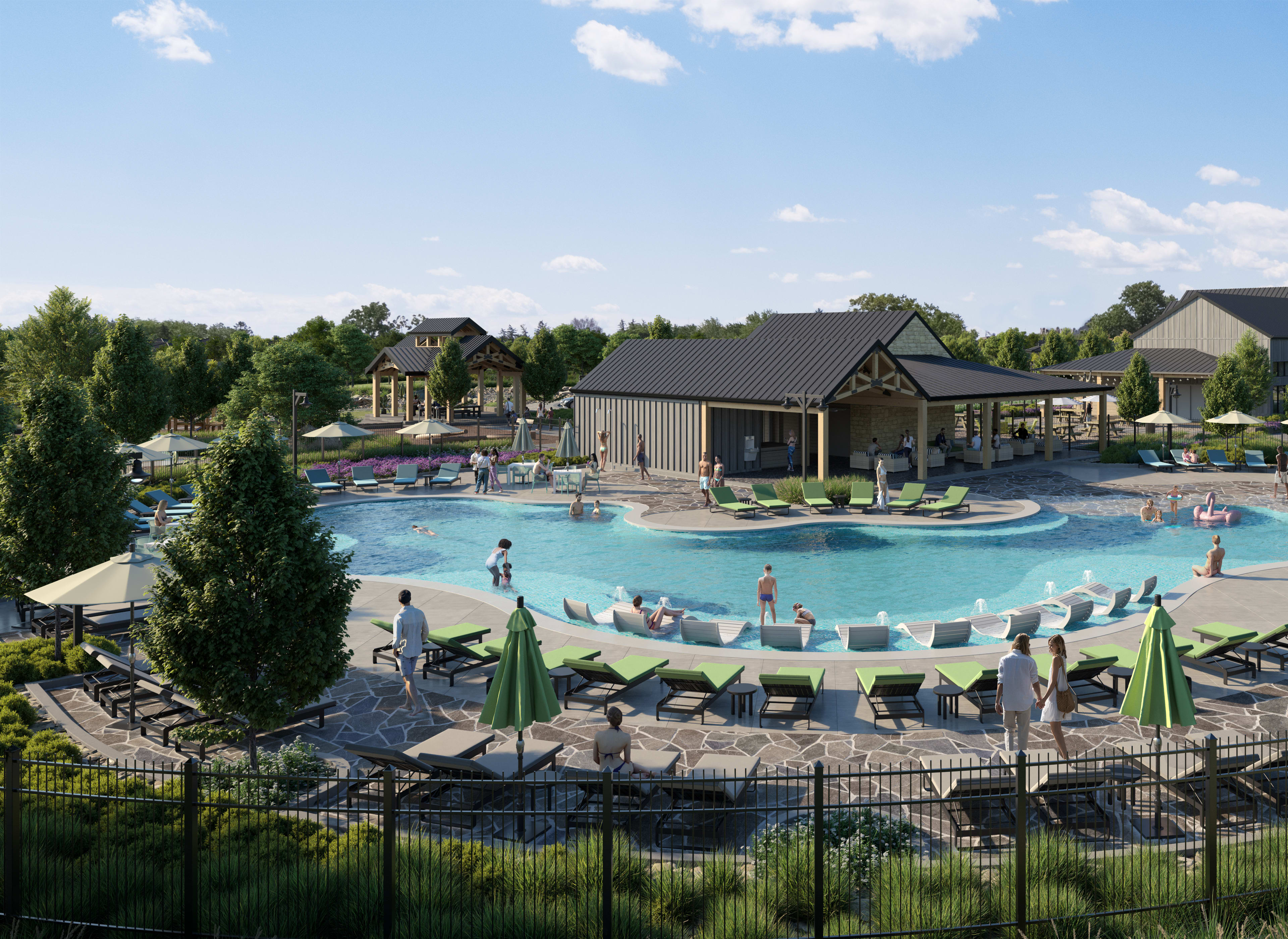 A large outdoor swimming pool surrounded by lounge chairs and umbrellas, with a cluster of buildings and trees in the background.