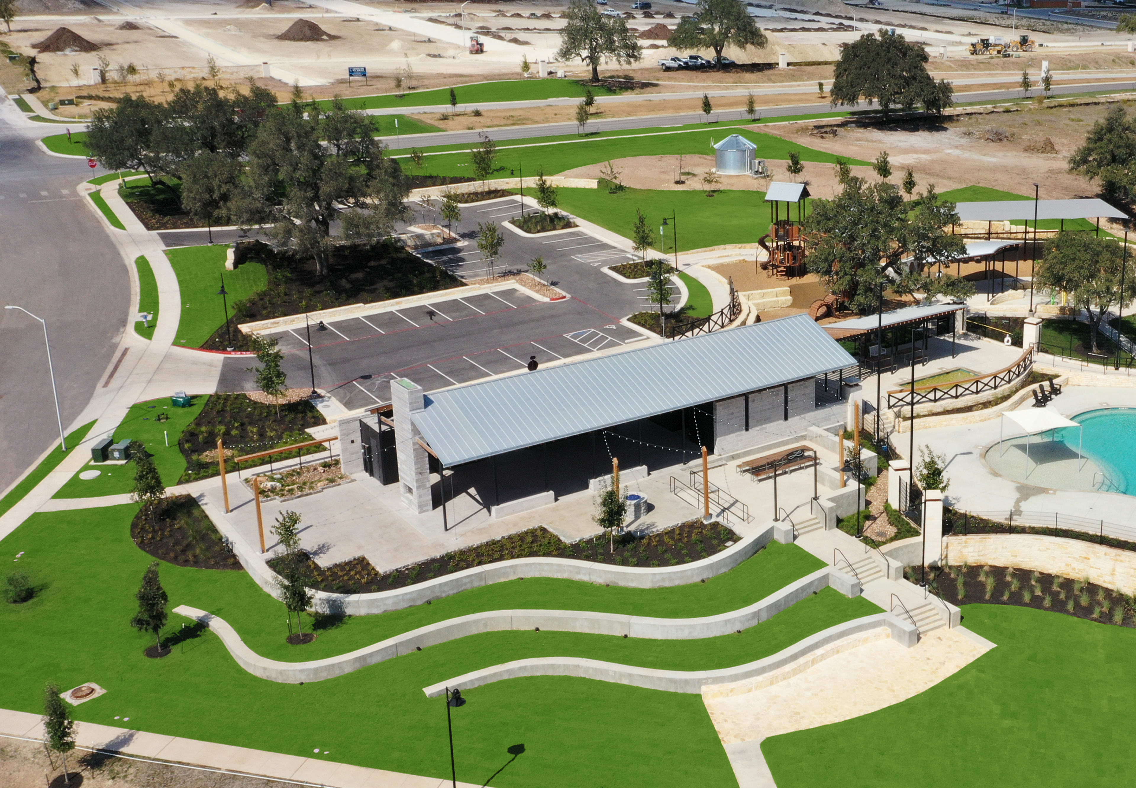 A sprawling architectural complex with domed structures, landscaped gardens, and a swimming pool nestled amidst a hilly, wooded environment.