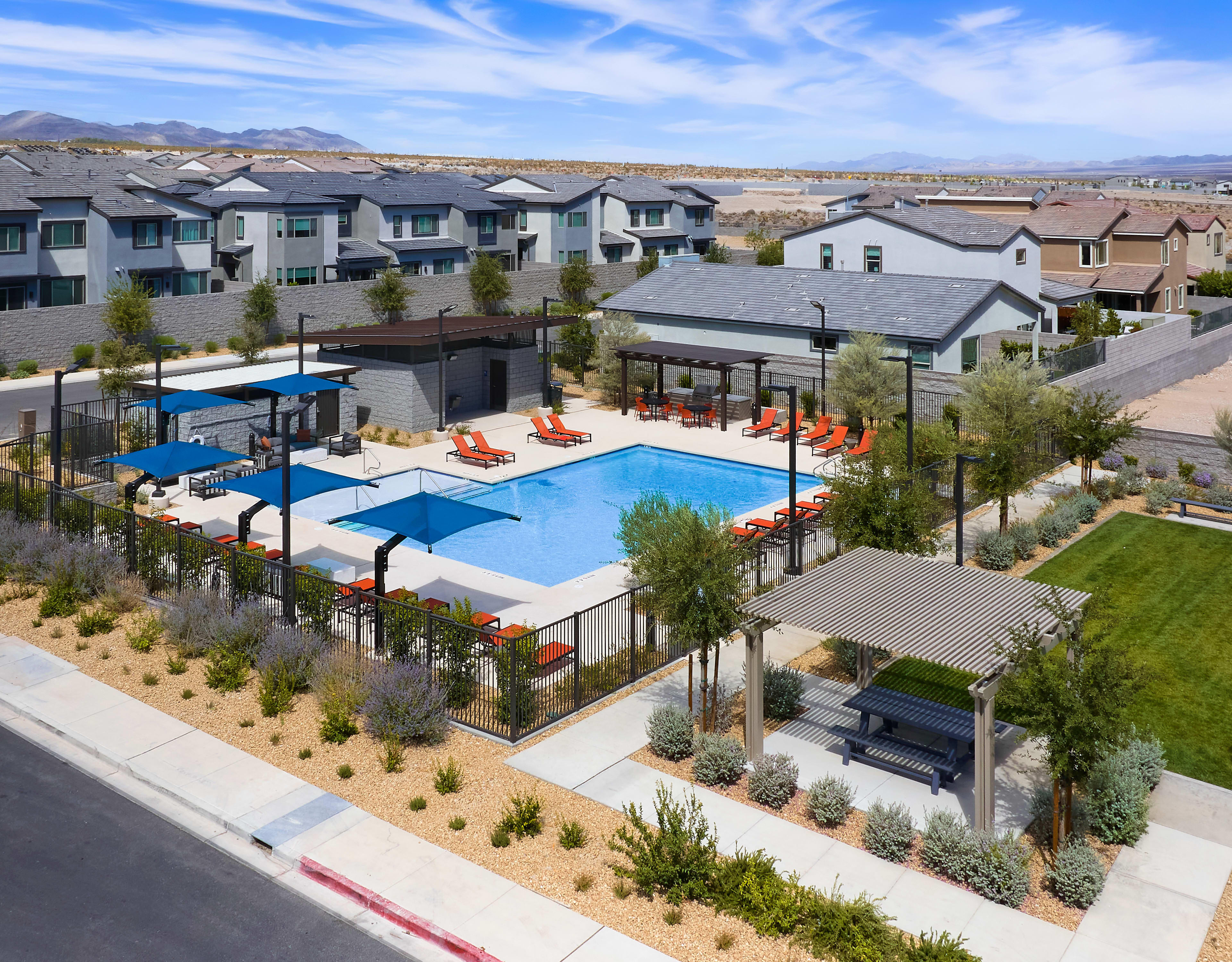 A residential community with a central swimming pool surrounded by landscaped grounds, with mountains visible in the background.