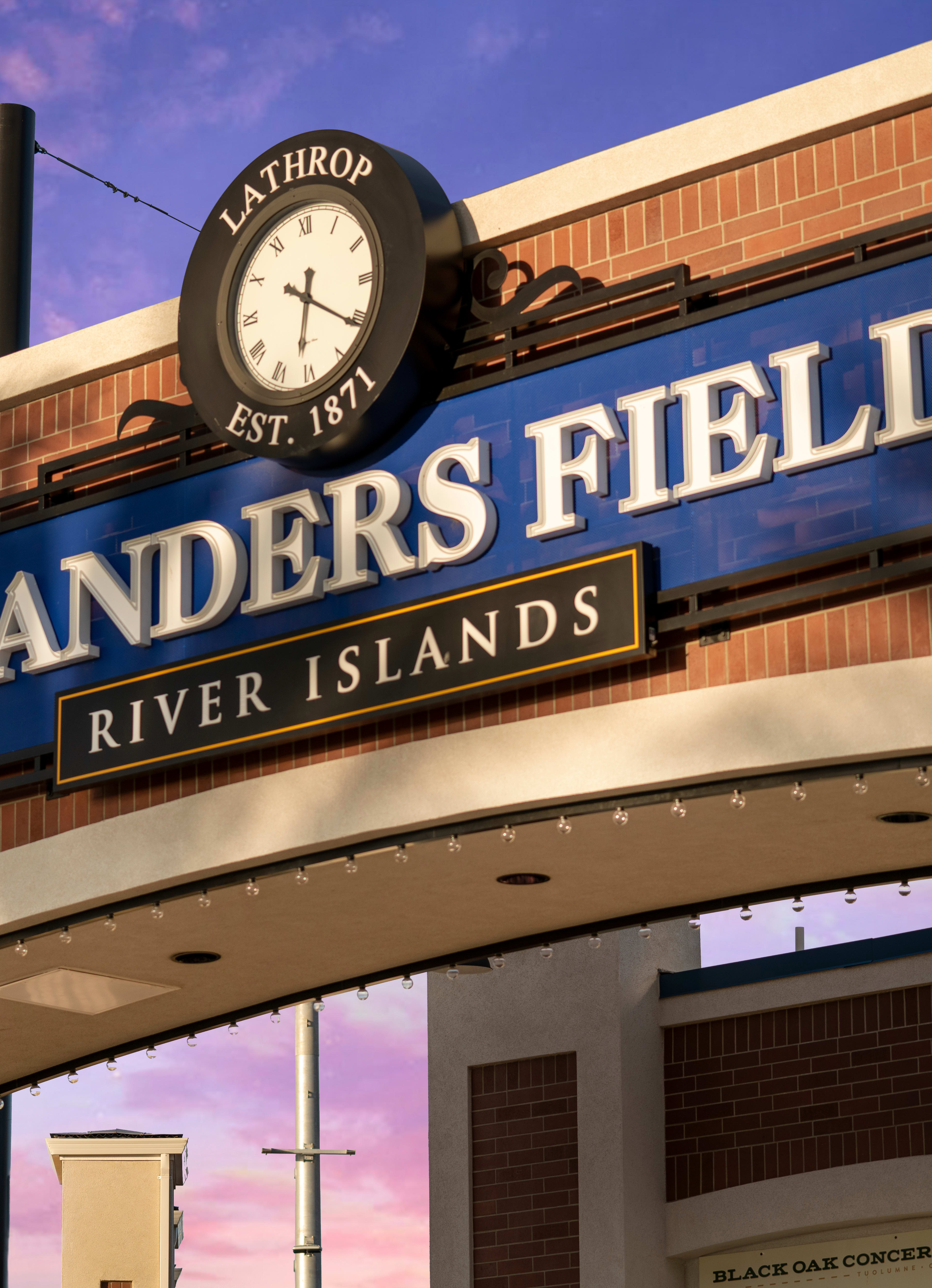 A brick building with a large sign reading "Islanders Field" and a clock tower, set against a vibrant purple and blue sky.