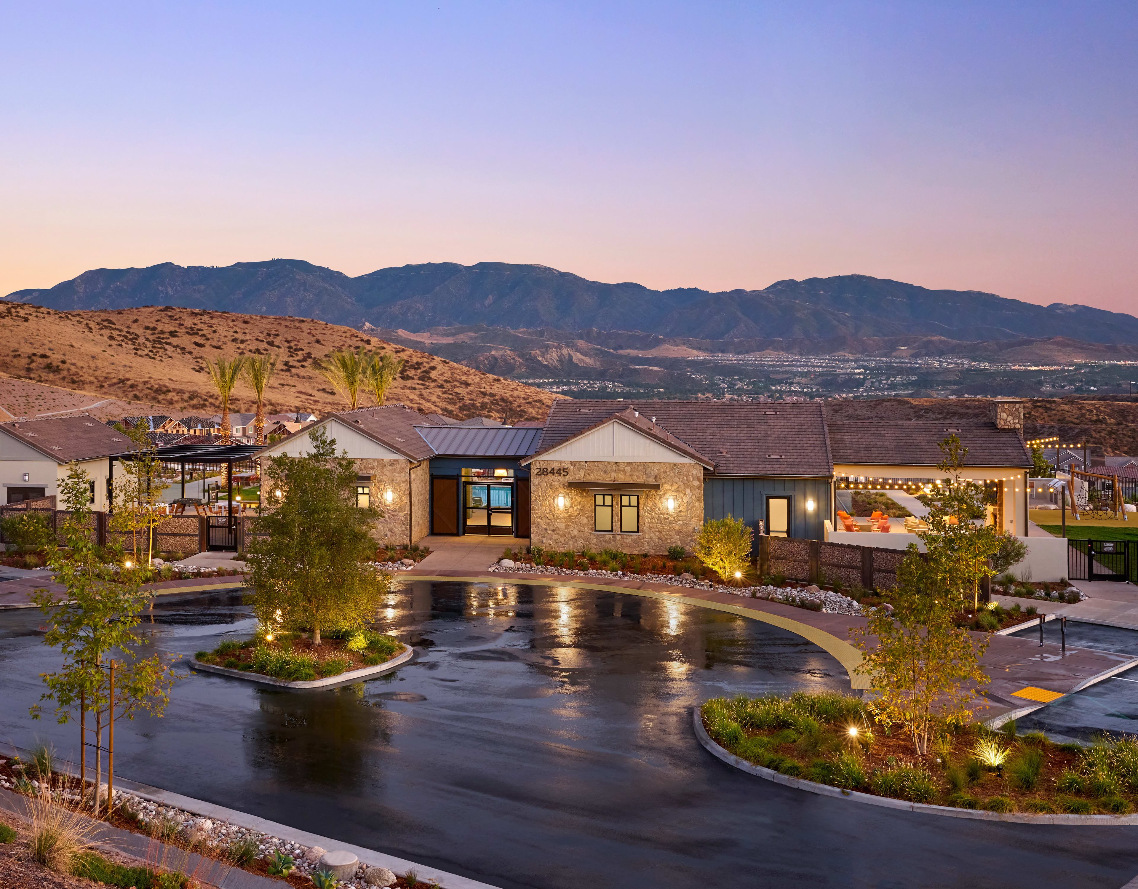 A tranquil outdoor setting with a pond surrounded by lush greenery, against the backdrop of a mountainous landscape bathed in the warm glow of sunset.
