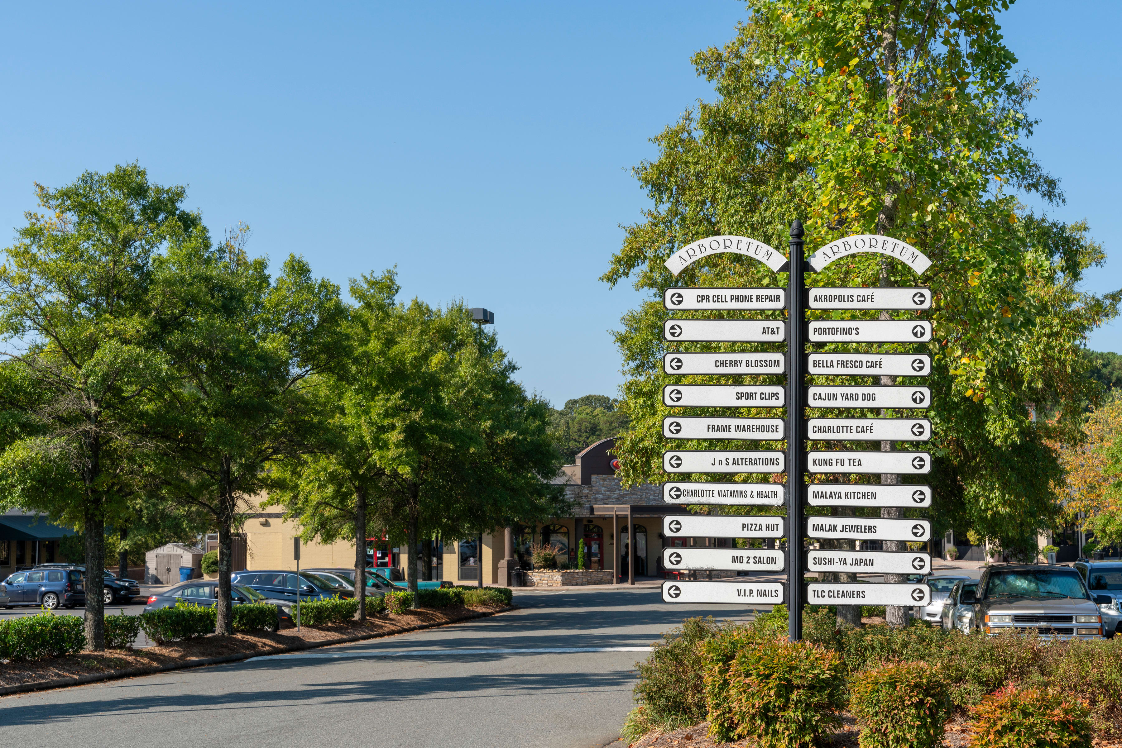 A street lined with trees and directional signs pointing to various local attractions and destinations.