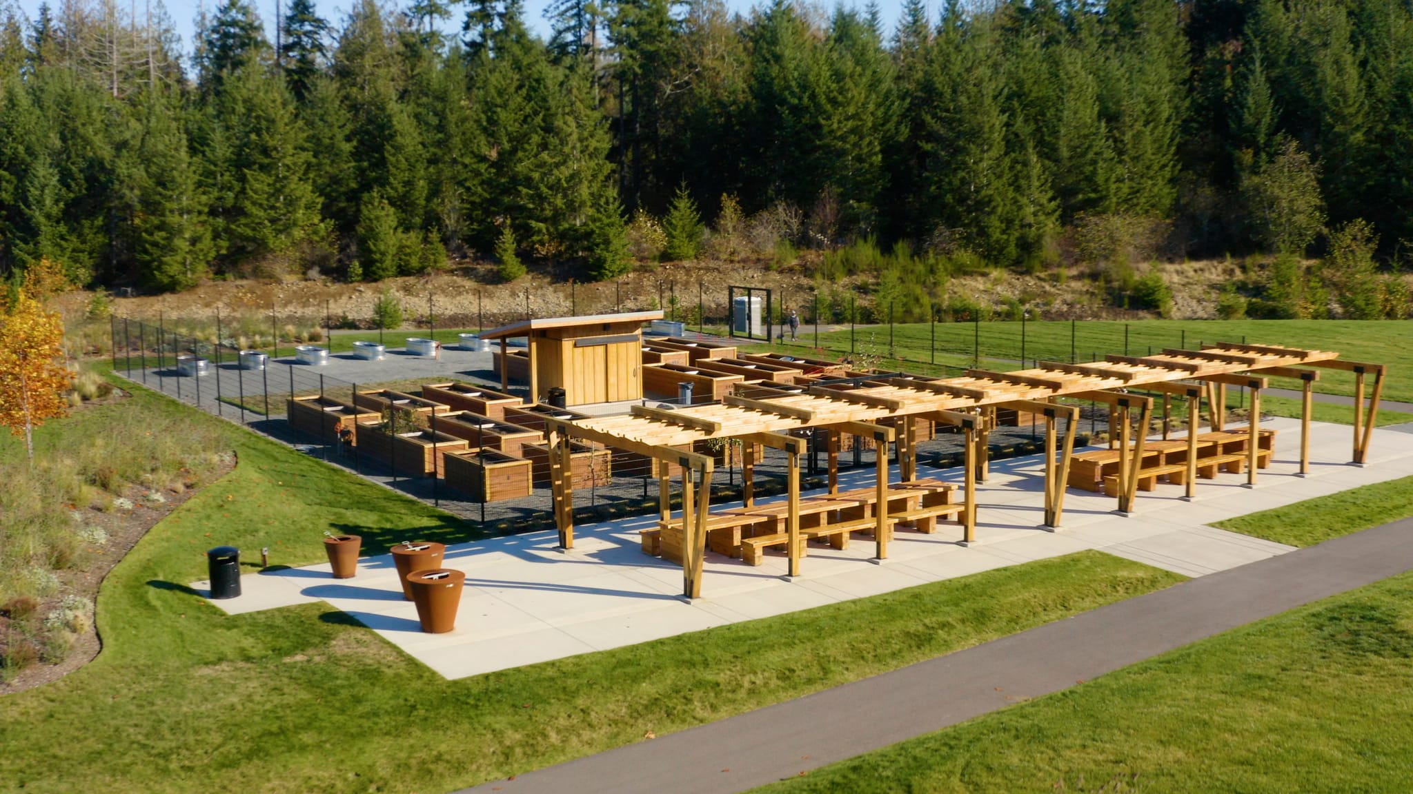 An outdoor seating area with wooden tables and chairs surrounded by a lush forest landscape.