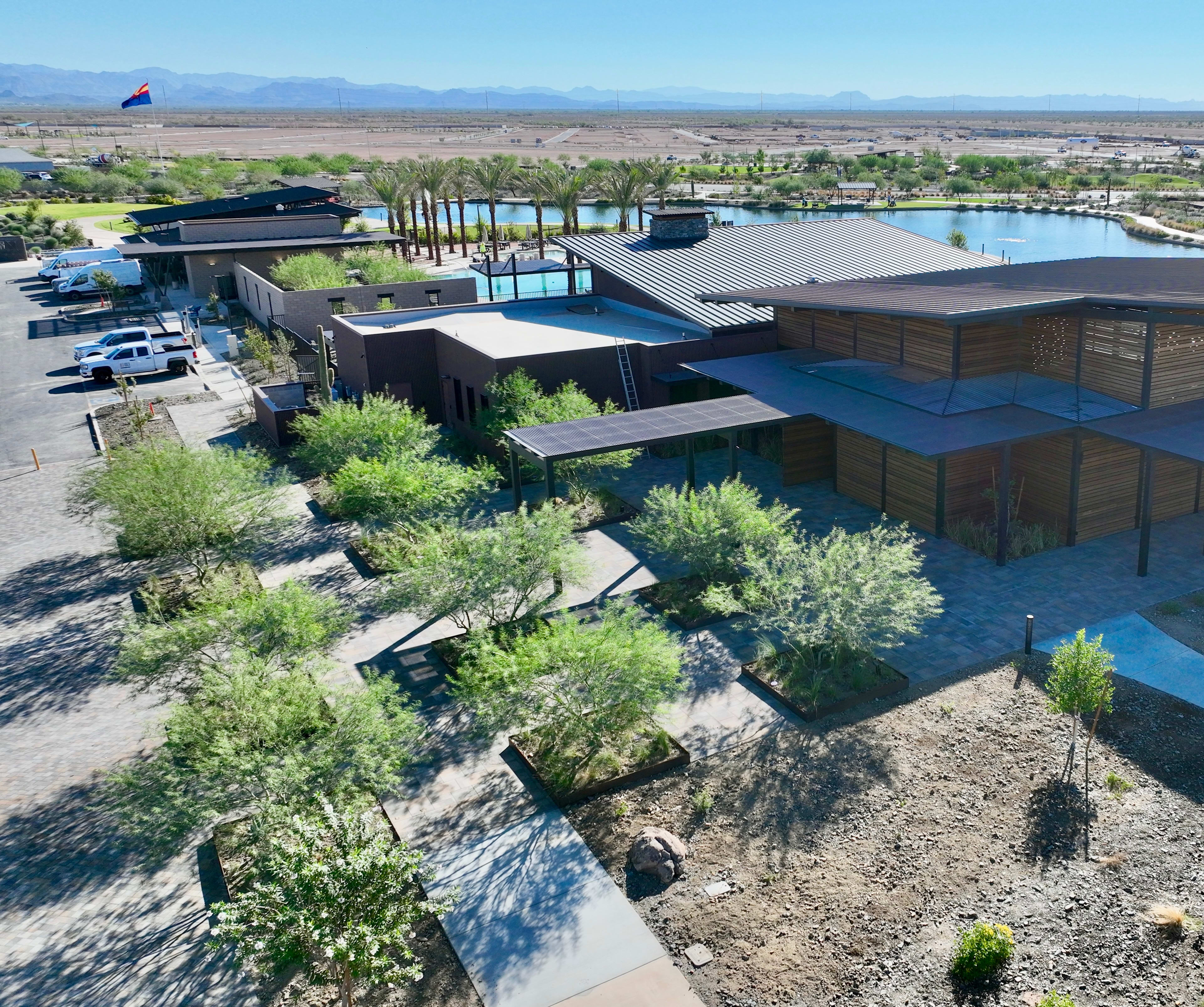 A modern, multi-level building with a distinctive architectural design sits amidst a lush, landscaped environment, overlooking a vast expanse of desert terrain and distant mountains.
