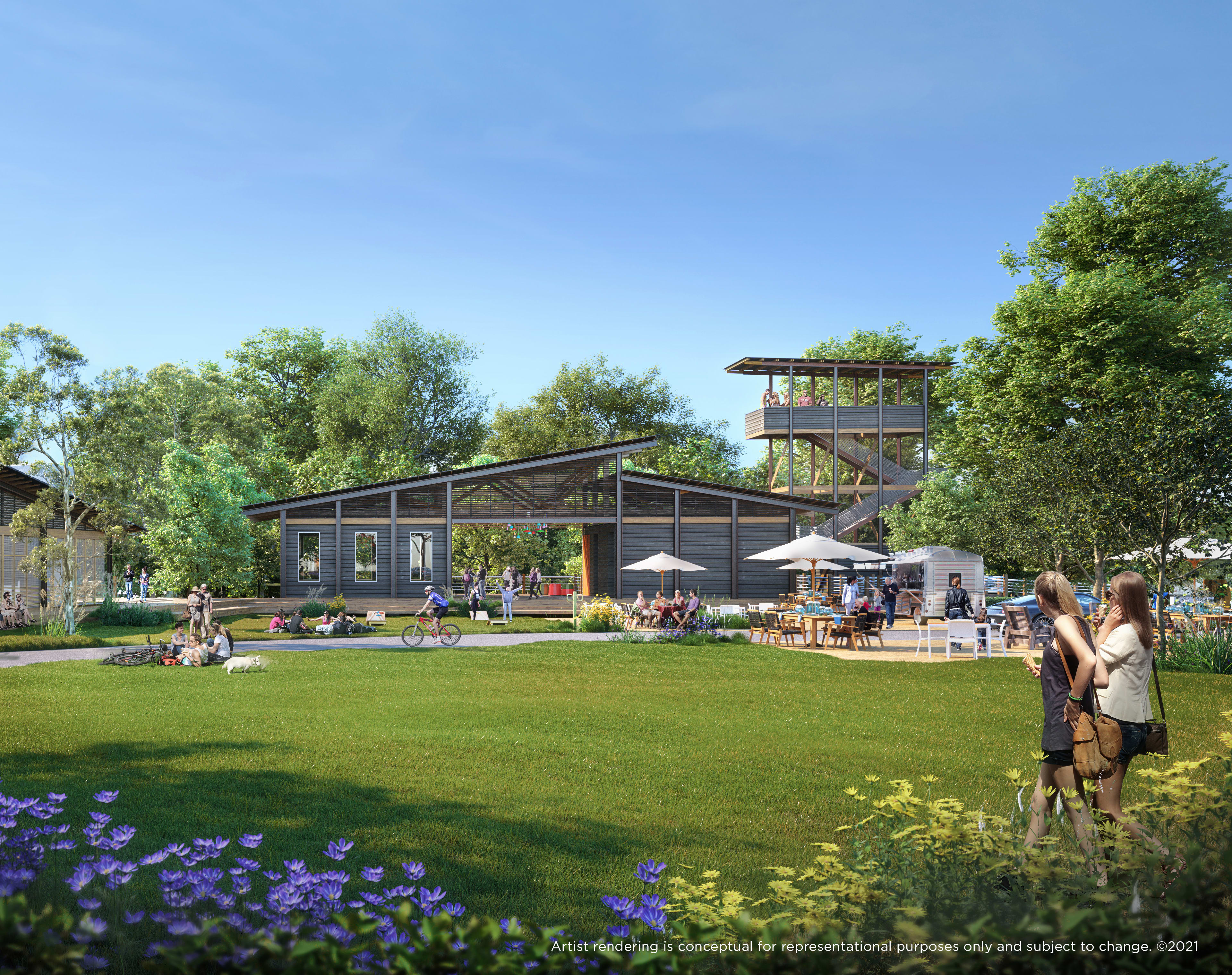 A lush green lawn surrounded by colorful flowers and trees, with several buildings and structures in the background, creating a picturesque outdoor setting.