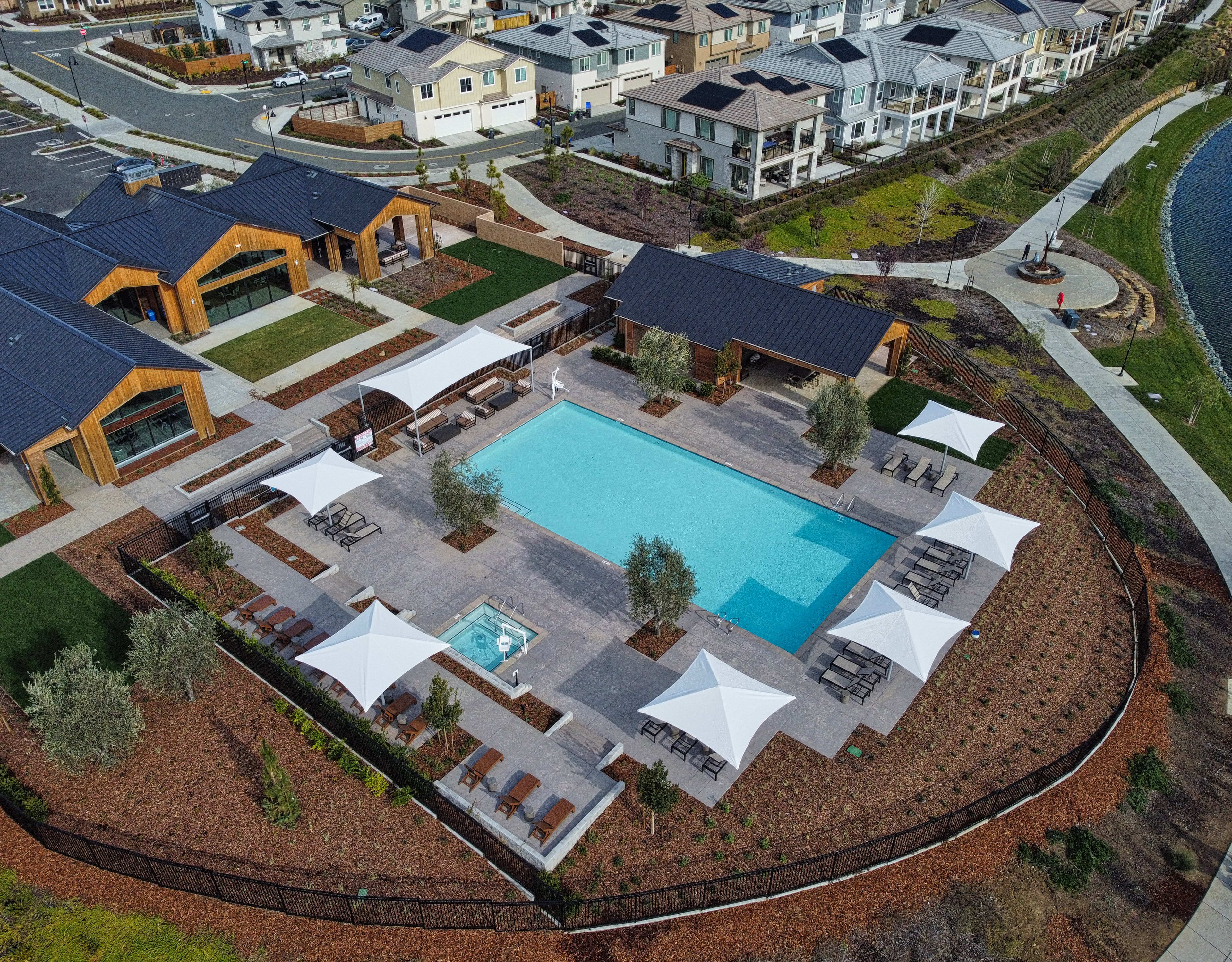 A residential community with a central swimming pool surrounded by various houses, patios, and landscaped areas.