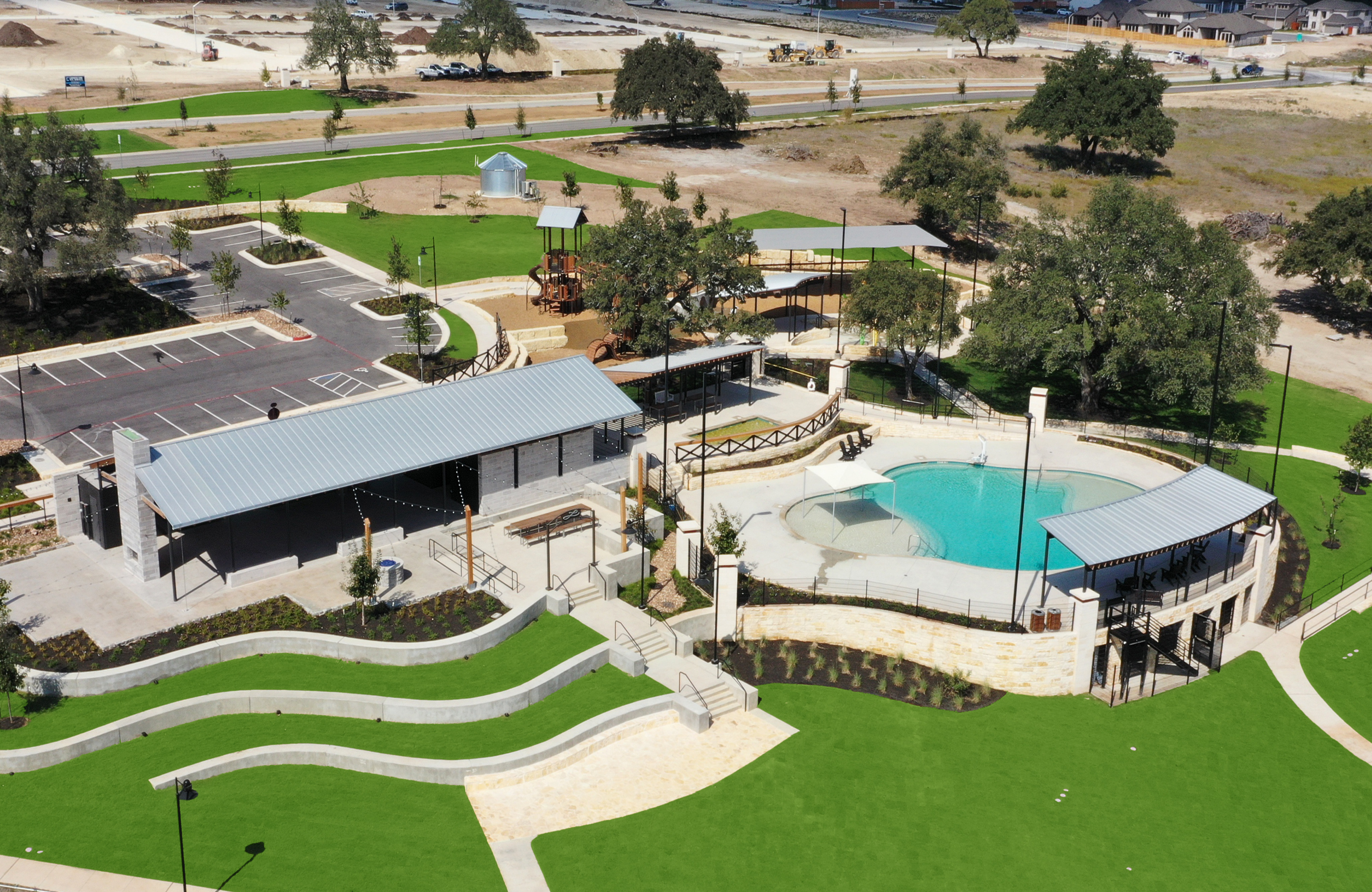 A sprawling architectural complex with domed structures, landscaped gardens, and a swimming pool nestled amidst a hilly, wooded environment.