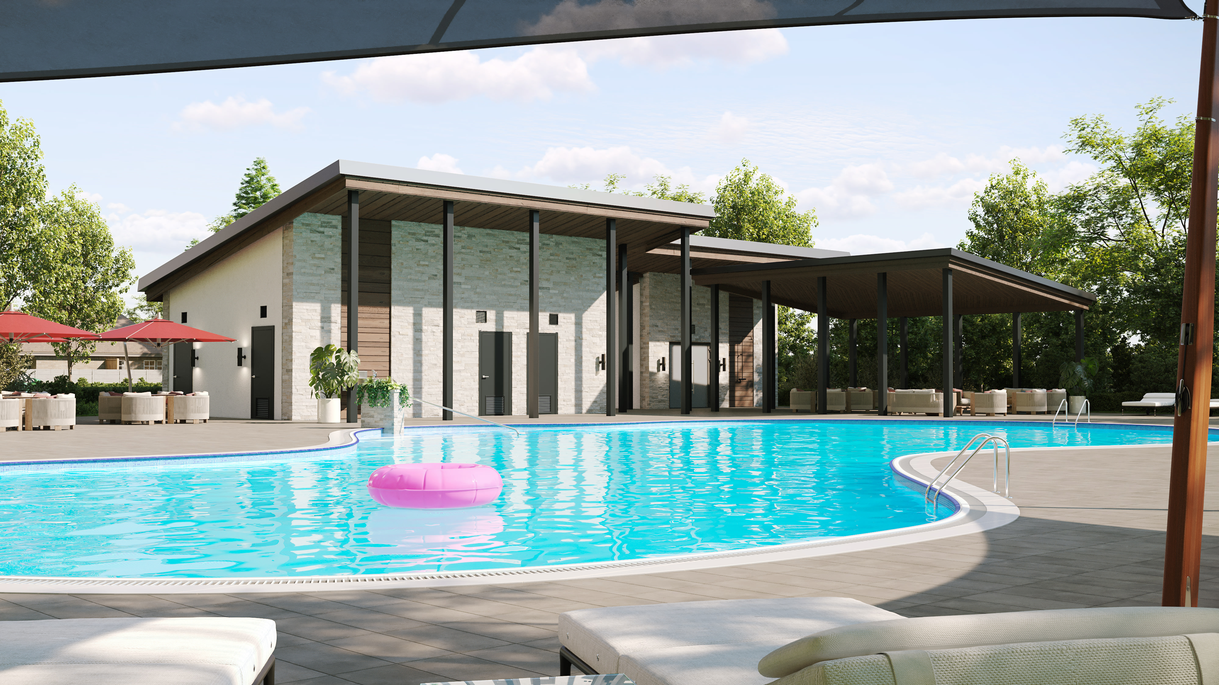 A modern, glass-walled building with a covered patio overlooks a large, crystal-clear swimming pool surrounded by lush greenery and a cloudy sky.