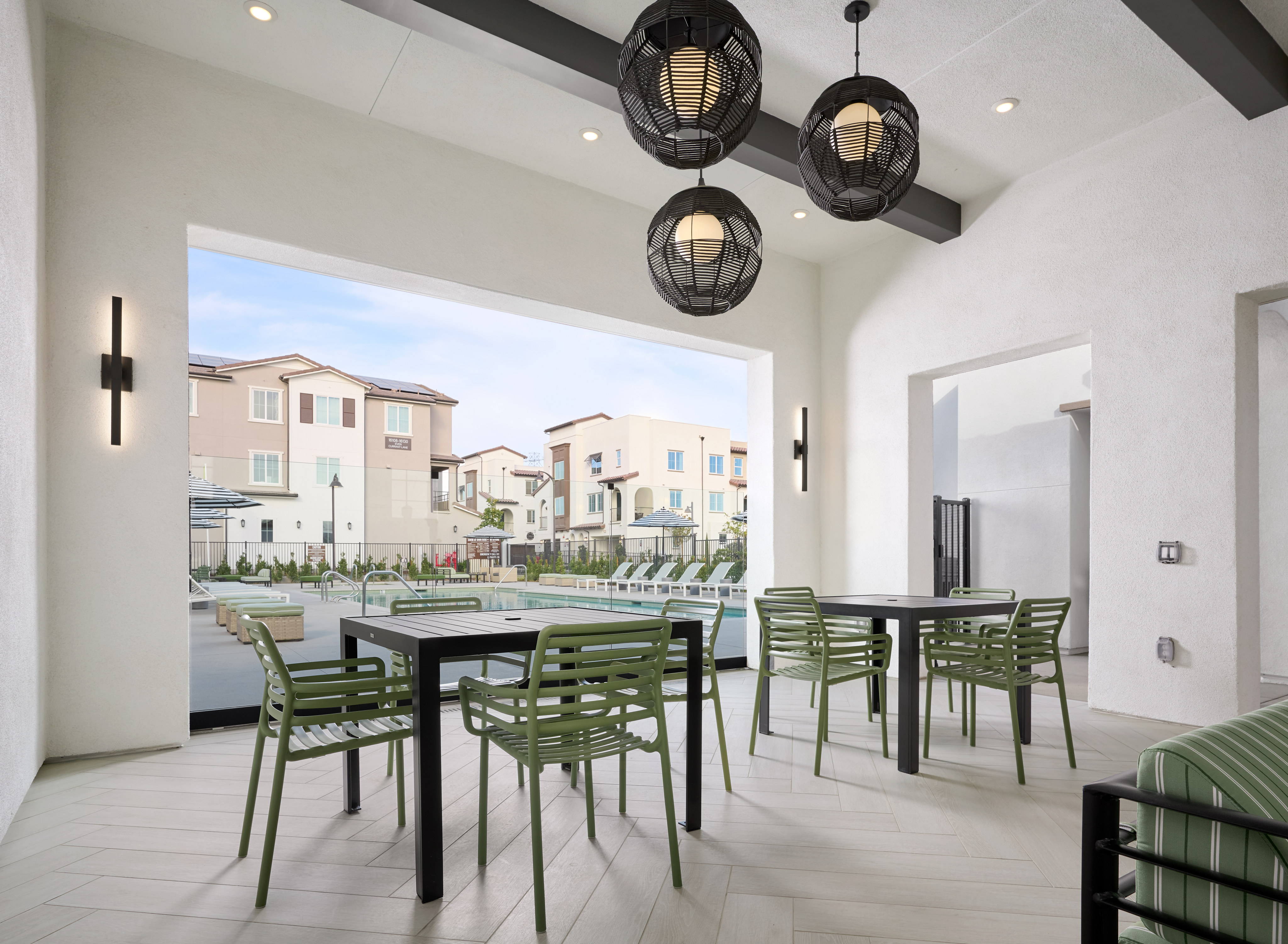 A modern and spacious dining area with a table and chairs, surrounded by a scenic outdoor view of a residential neighborhood through a large window.
