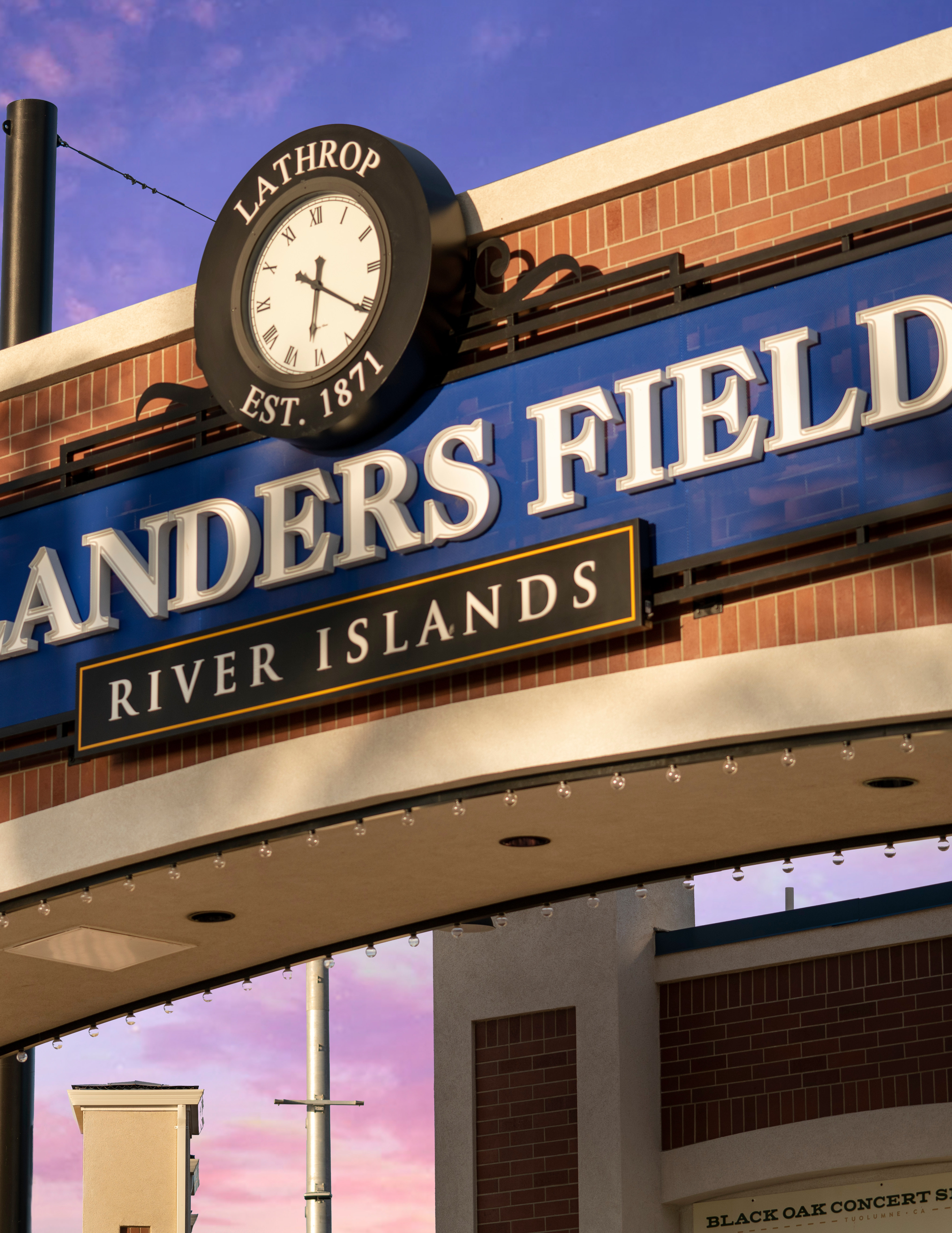 A brick building with a large sign reading "Islanders Field" and a clock tower, set against a vibrant purple and blue sky.