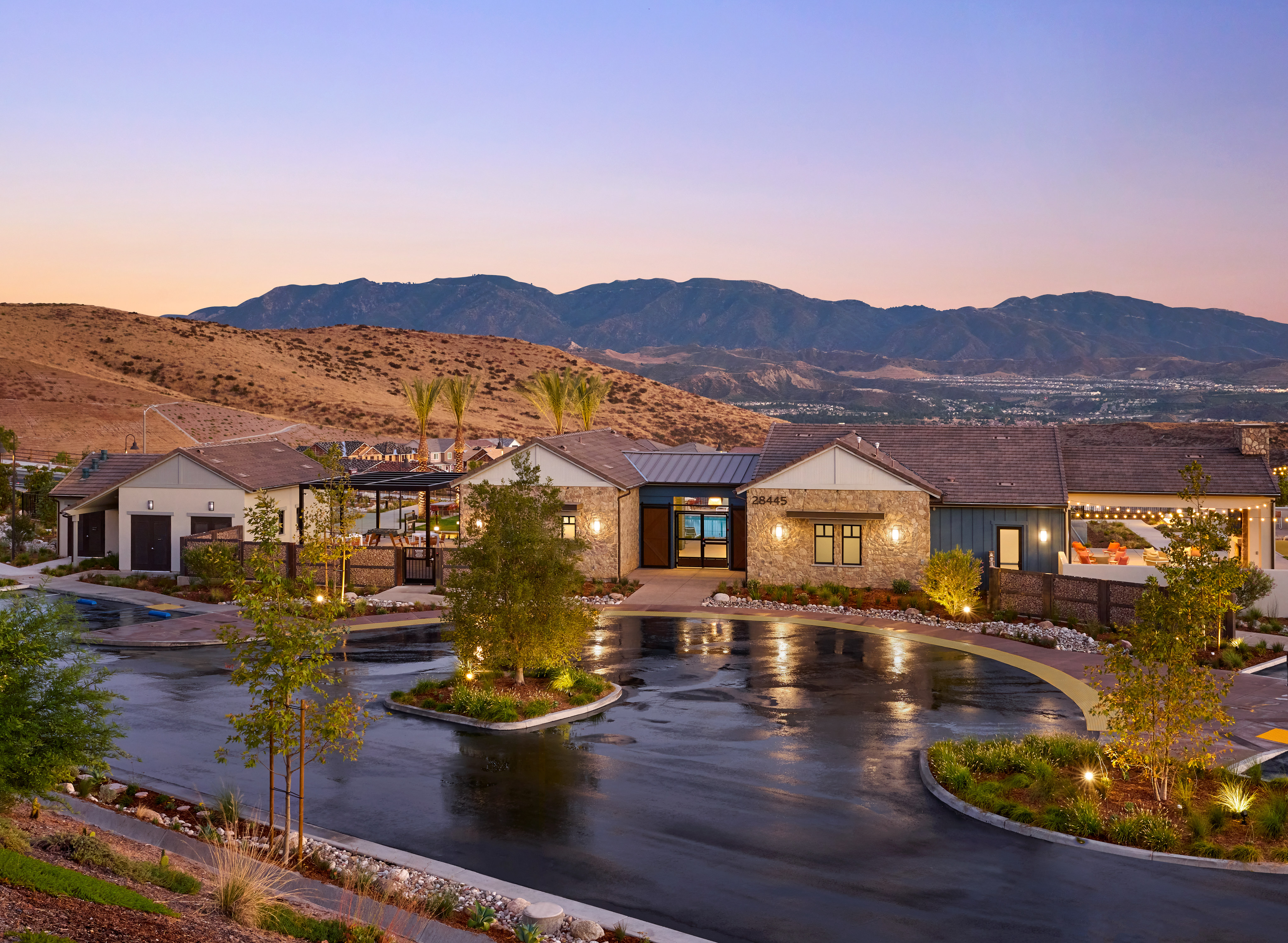 A tranquil outdoor setting with a pond surrounded by lush greenery, against the backdrop of a mountainous landscape bathed in the warm glow of sunset.