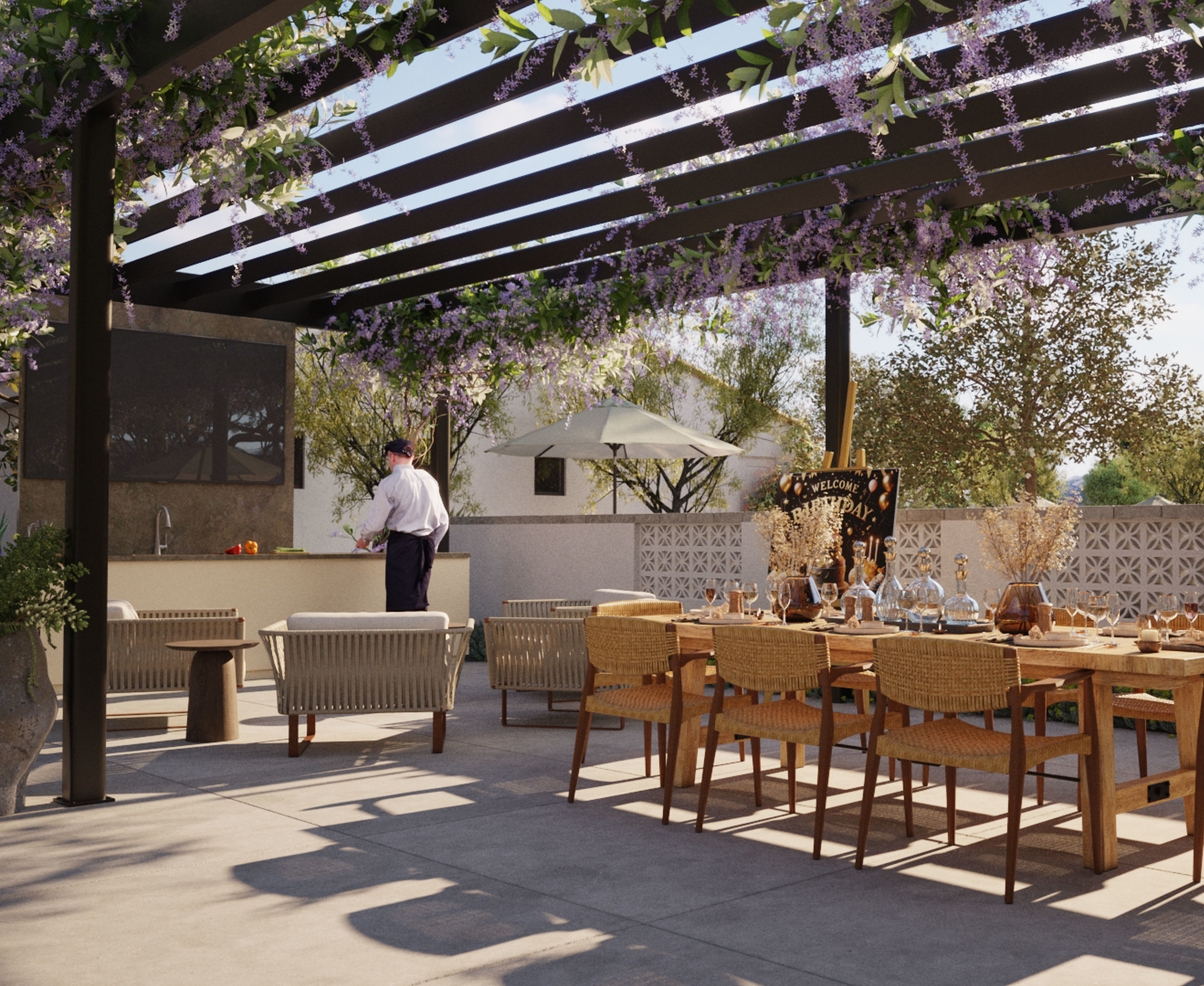 An outdoor dining area with a wooden pergola overhead, surrounded by lush greenery and potted plants, with a table and chairs set up for an alfresco meal.
