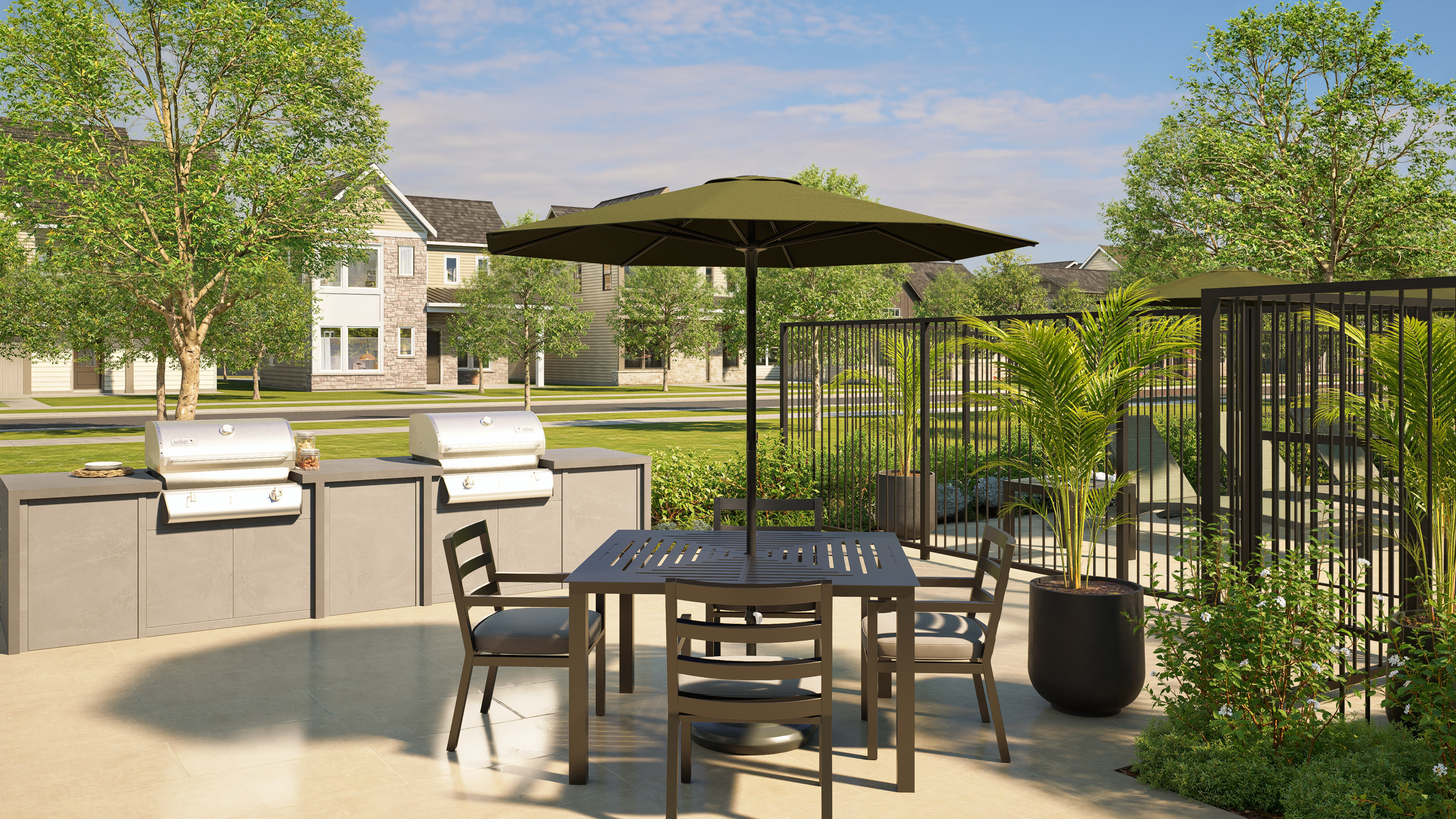 A patio with a table and chairs sits in the foreground, while grills and apartment buildings are visible in the background.