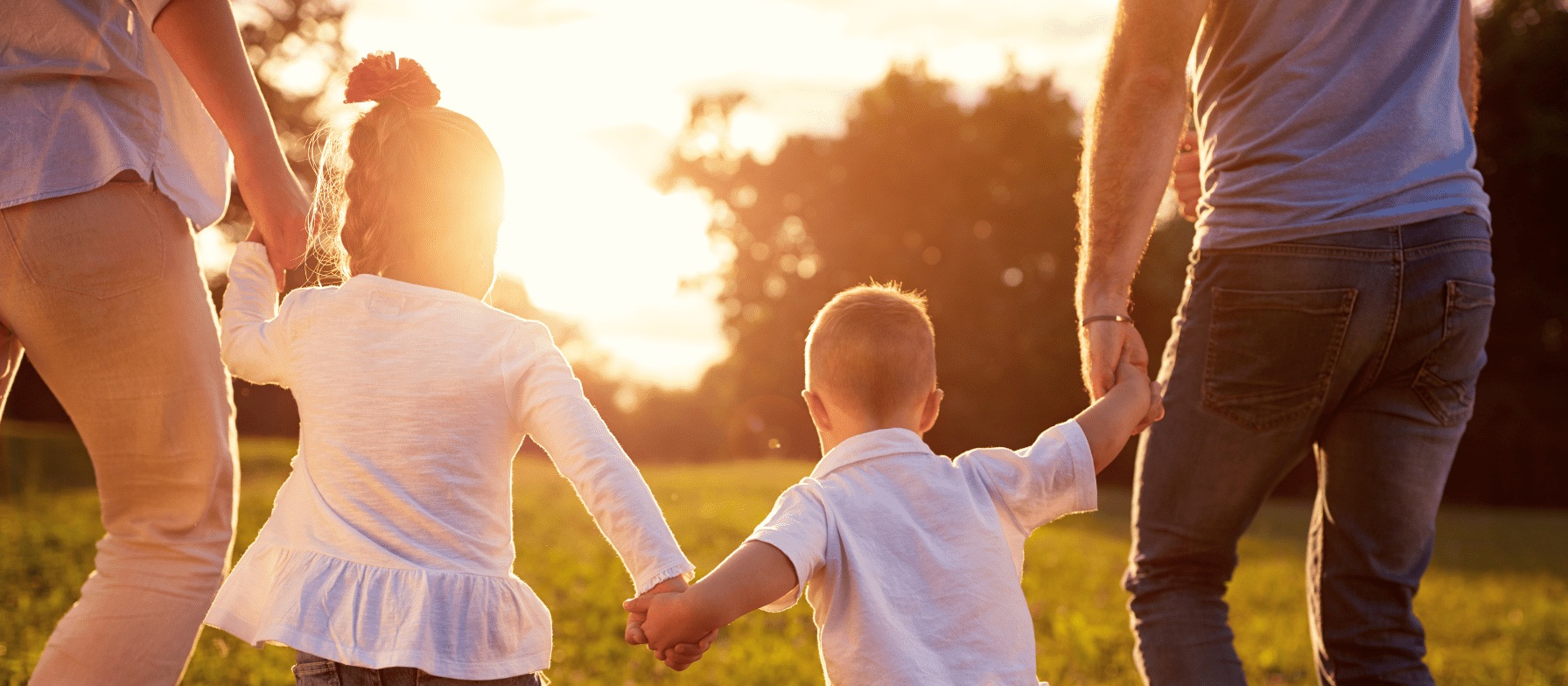 A group of people, likely a family, walking together in a serene outdoor setting with a warm, golden sunset in the background.