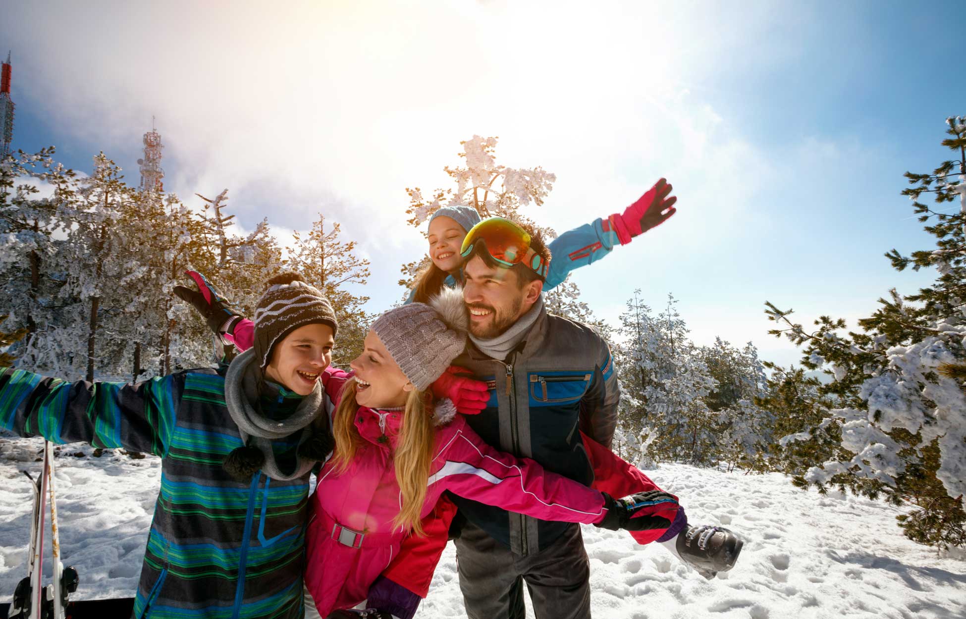 A group of people enjoying a snowy winter day, with colorful clothing and outdoor gear, surrounded by a winter landscape of trees and snow.