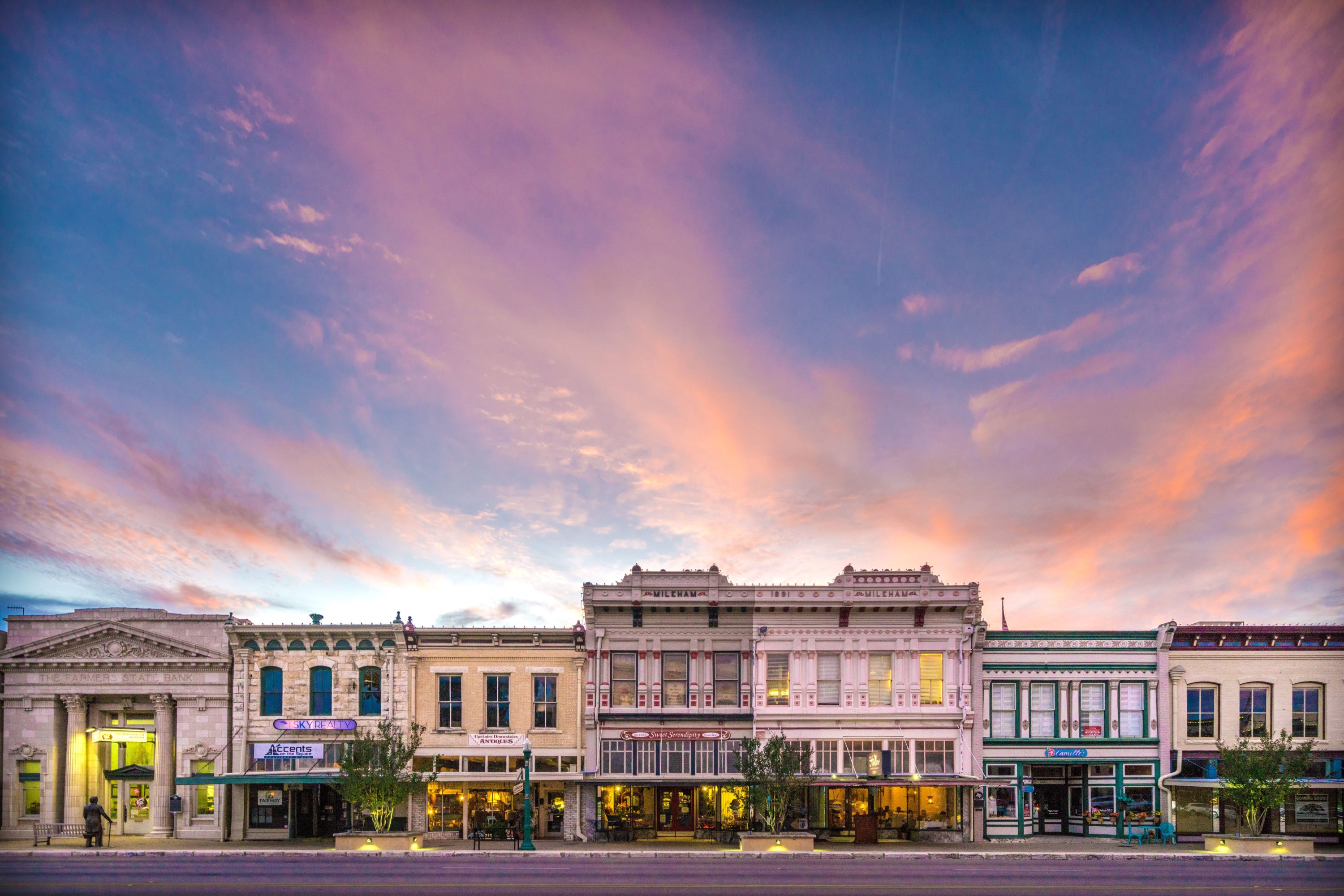 A vibrant and colorful sunset illuminates the historic buildings lining the street, creating a warm and inviting atmosphere in the foreground.