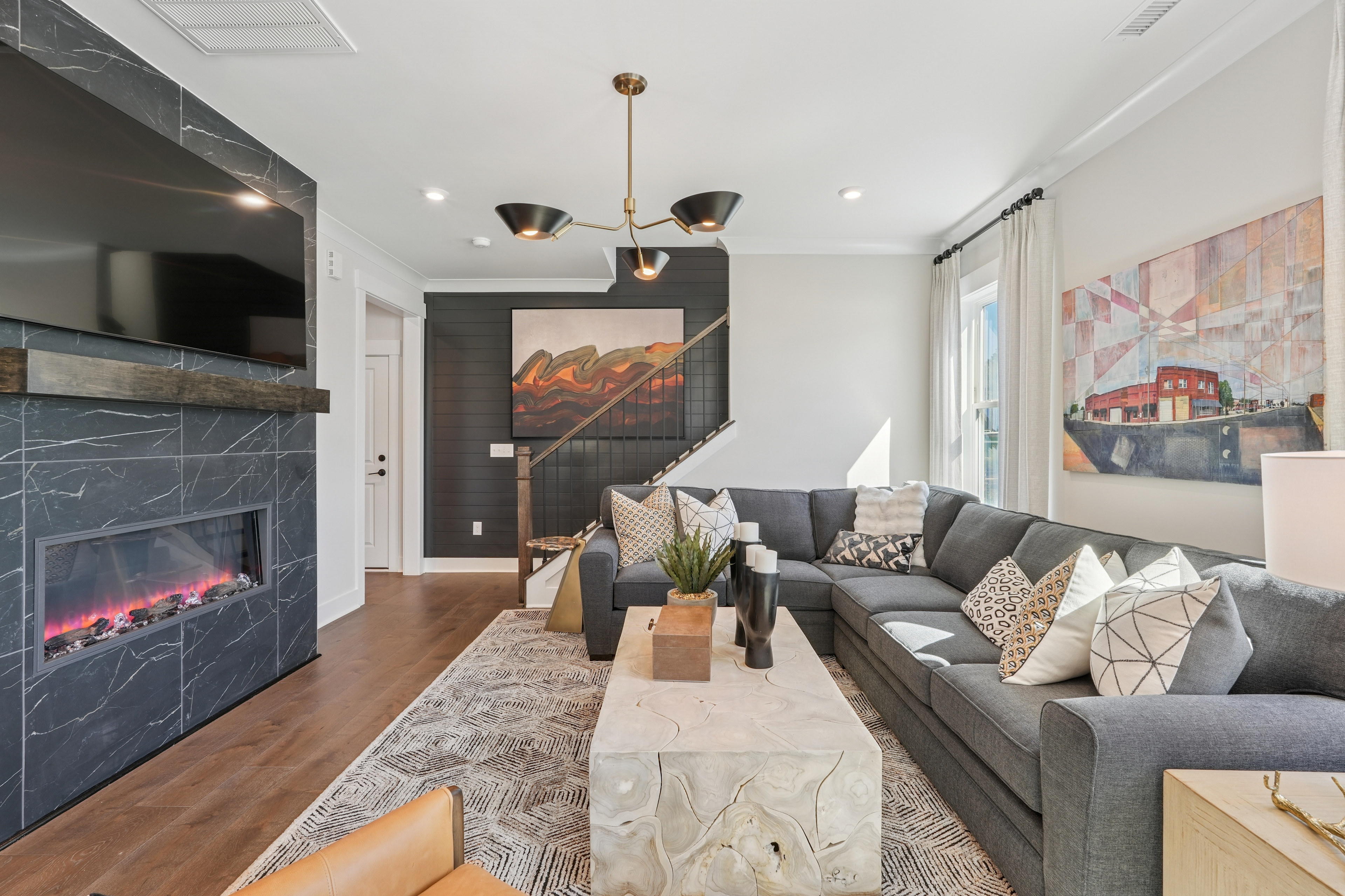 A modern and stylish living room with a gray sectional sofa, a fireplace with a slate surround, and artwork on the walls, creating a cozy and inviting atmosphere.