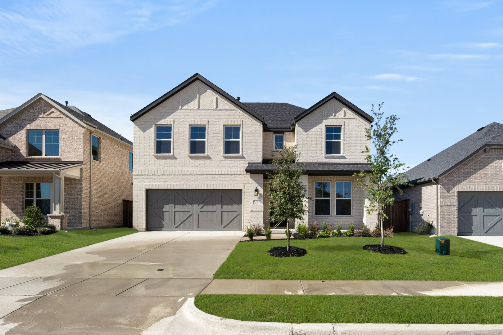 A two-story residential house with a garage, surrounded by a well-manicured lawn and other houses in a suburban neighborhood.