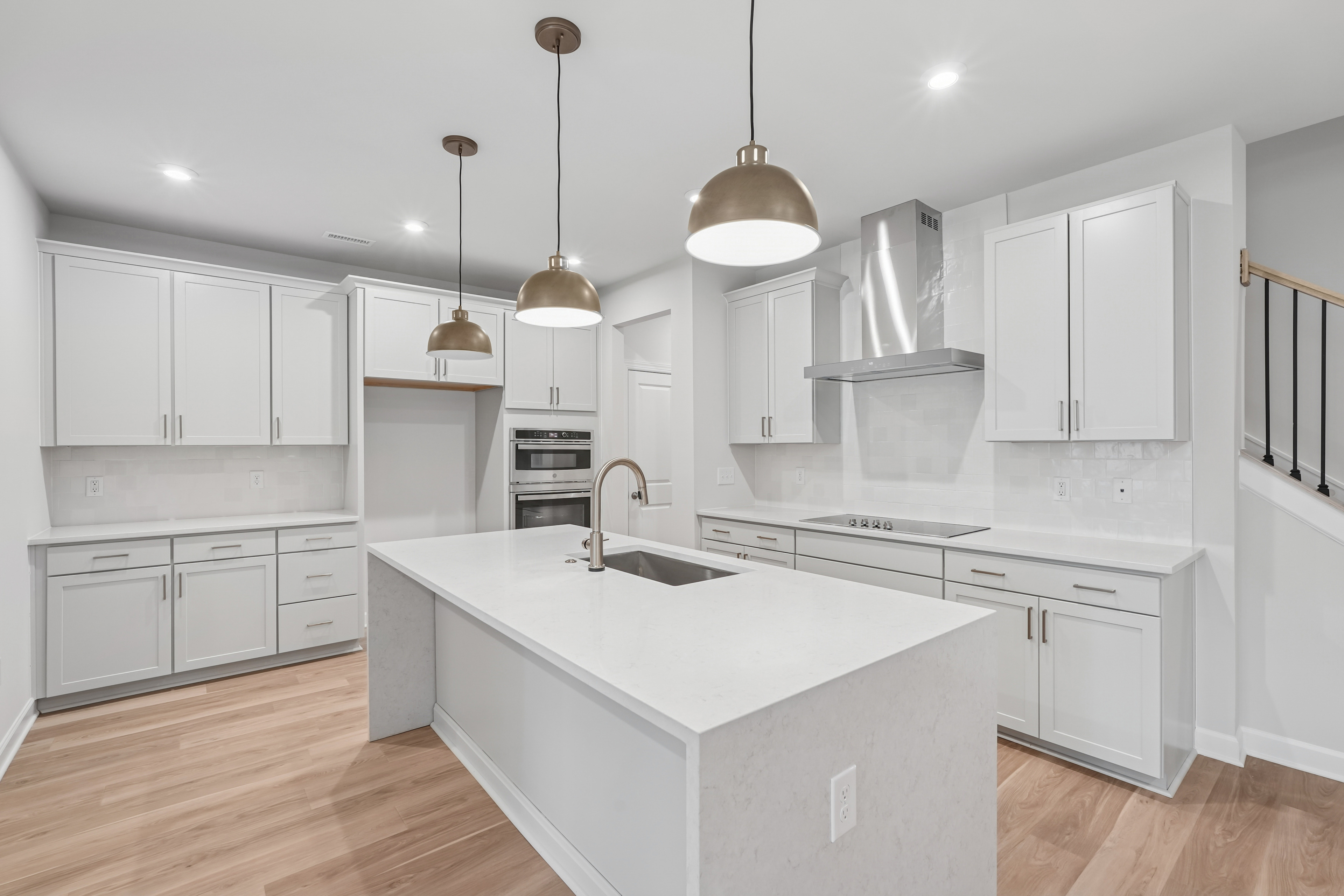 A modern, bright, and spacious kitchen with white cabinets, a large island, and pendant lighting fixtures.