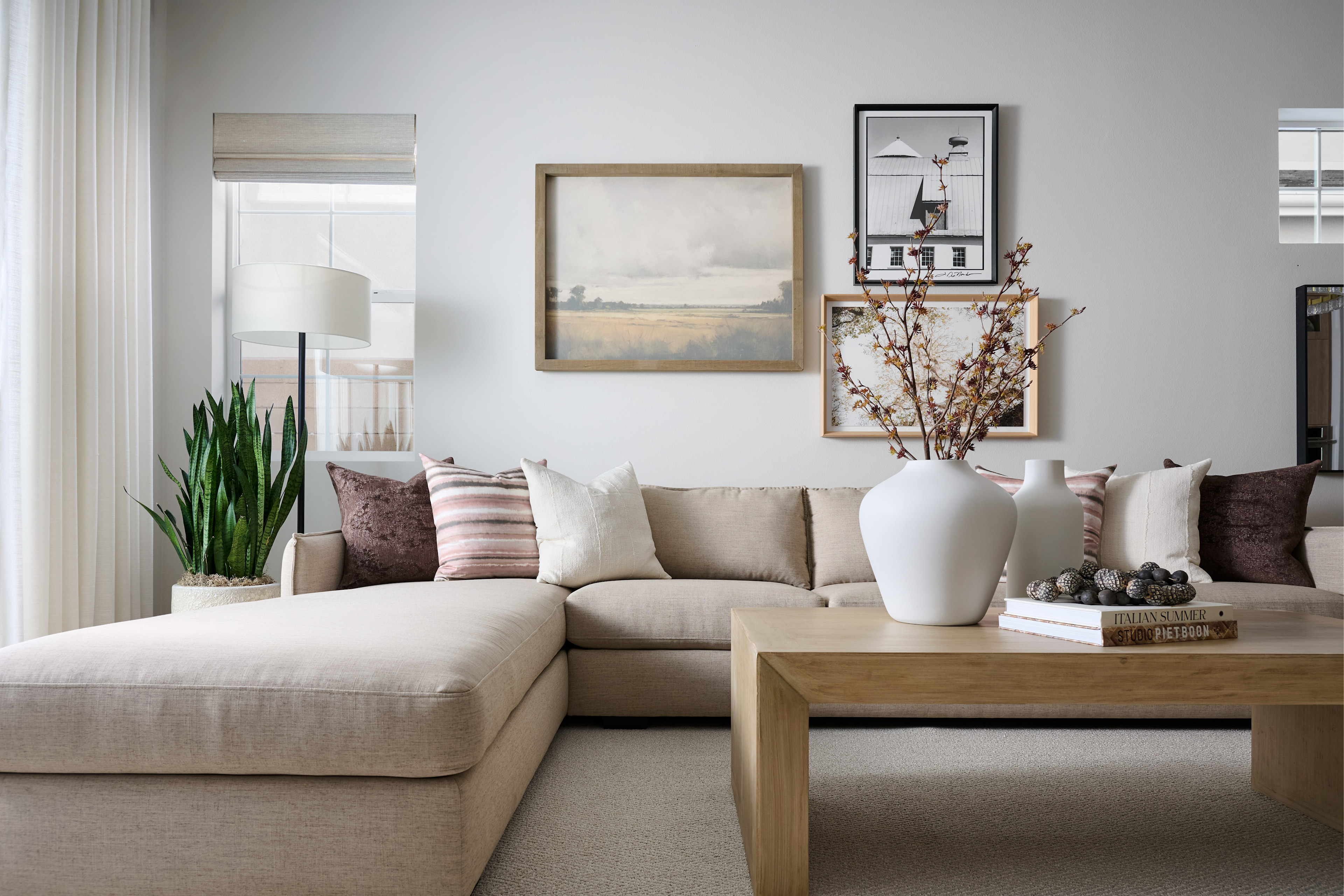 A cozy and inviting living room with a beige sectional sofa, a wooden coffee table, and various decorative elements such as artwork, vases, and plants, creating a warm and harmonious atmosphere.