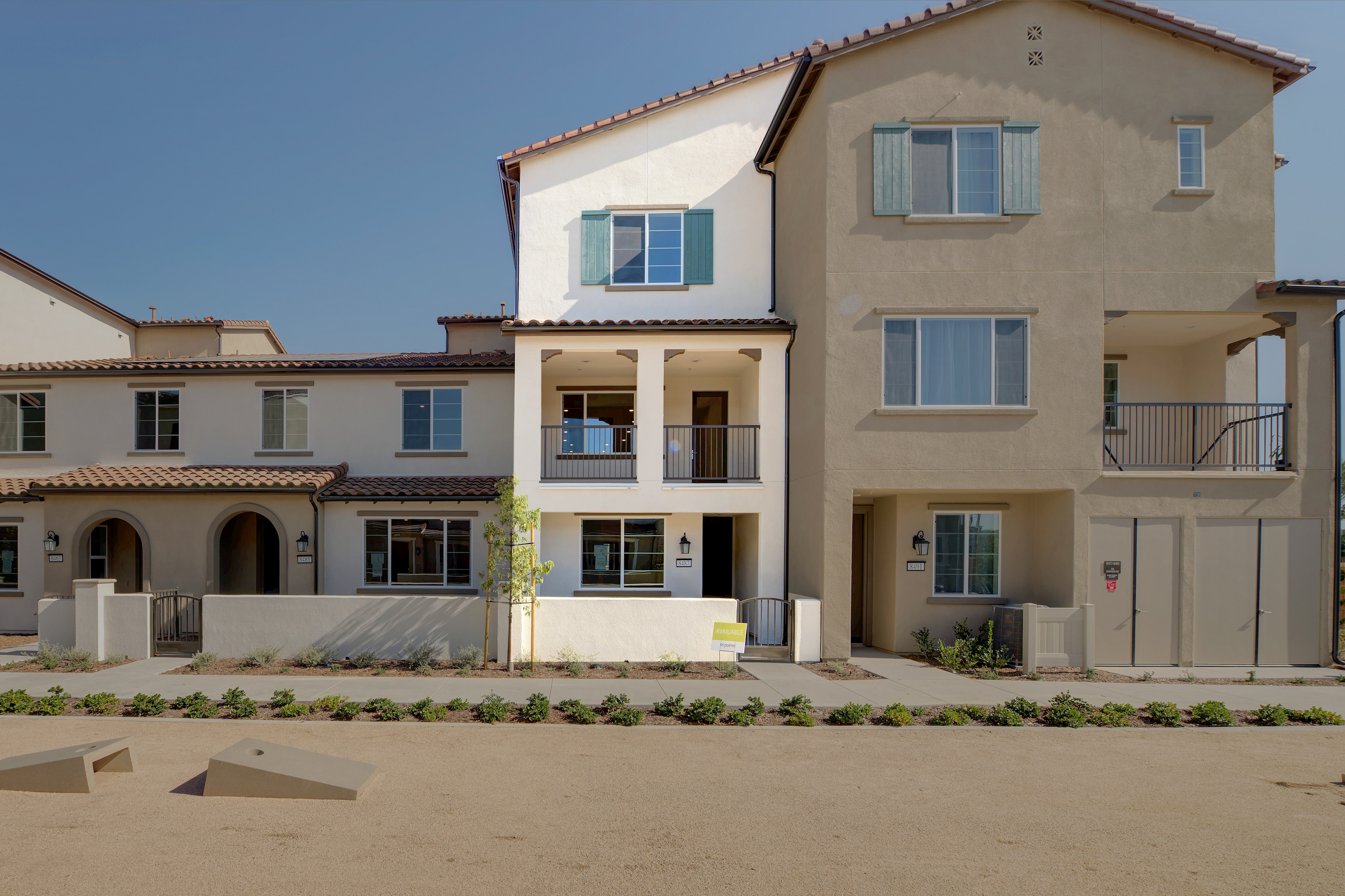 A multi-story residential building with a Mediterranean-style architecture, surrounded by a well-manicured landscaped area in the foreground.
