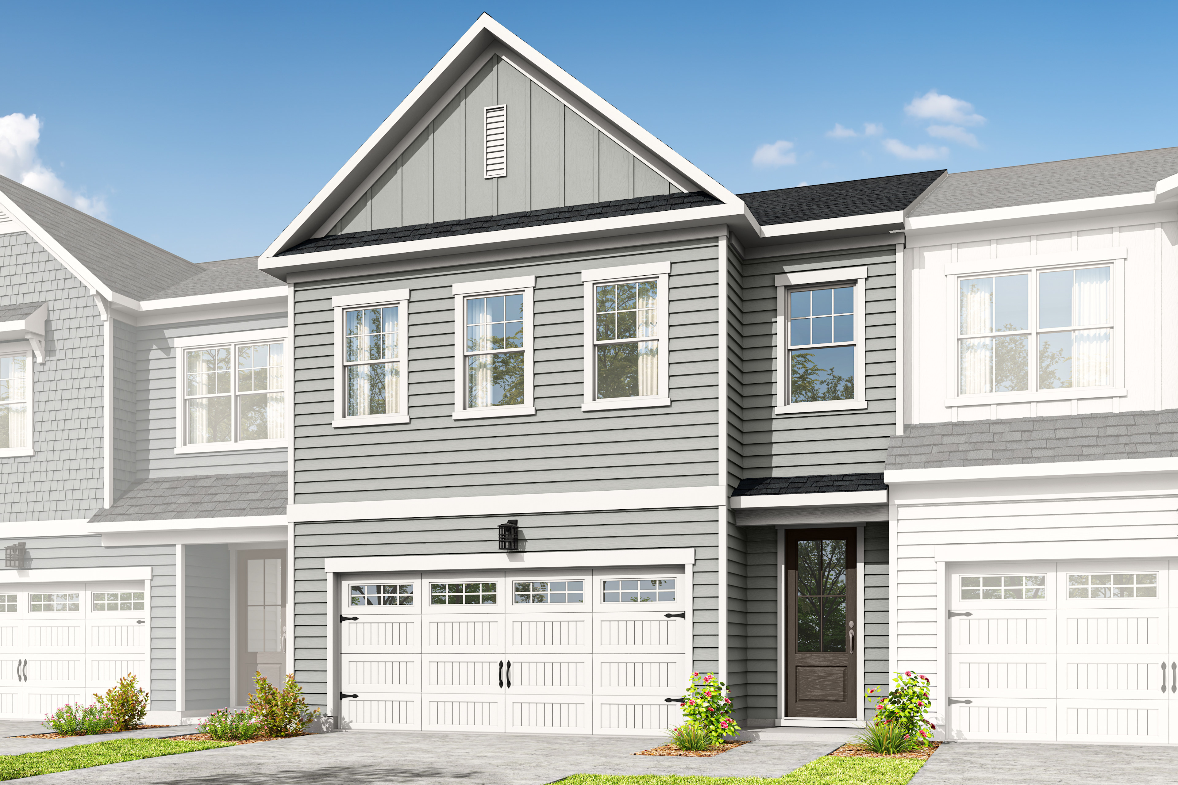 A two-story townhouse with a gray exterior, white trim, and a garage door in the foreground, set against a clear blue sky with some clouds in the background.
