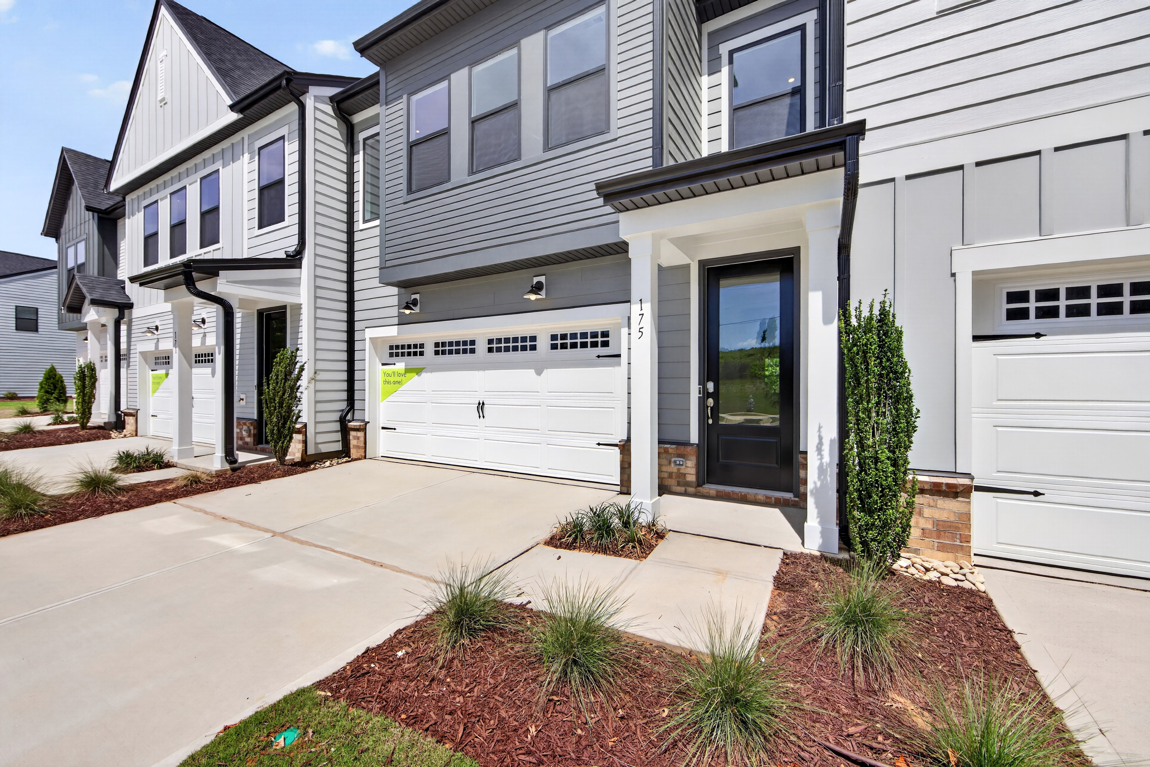 Modern townhouses with manicured landscaping in the foreground and a clear sky in the background.