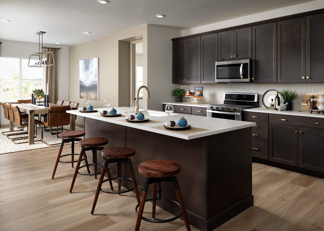 A modern and spacious kitchen with dark wood cabinets, a large island with bar stools, and various appliances and decor elements.