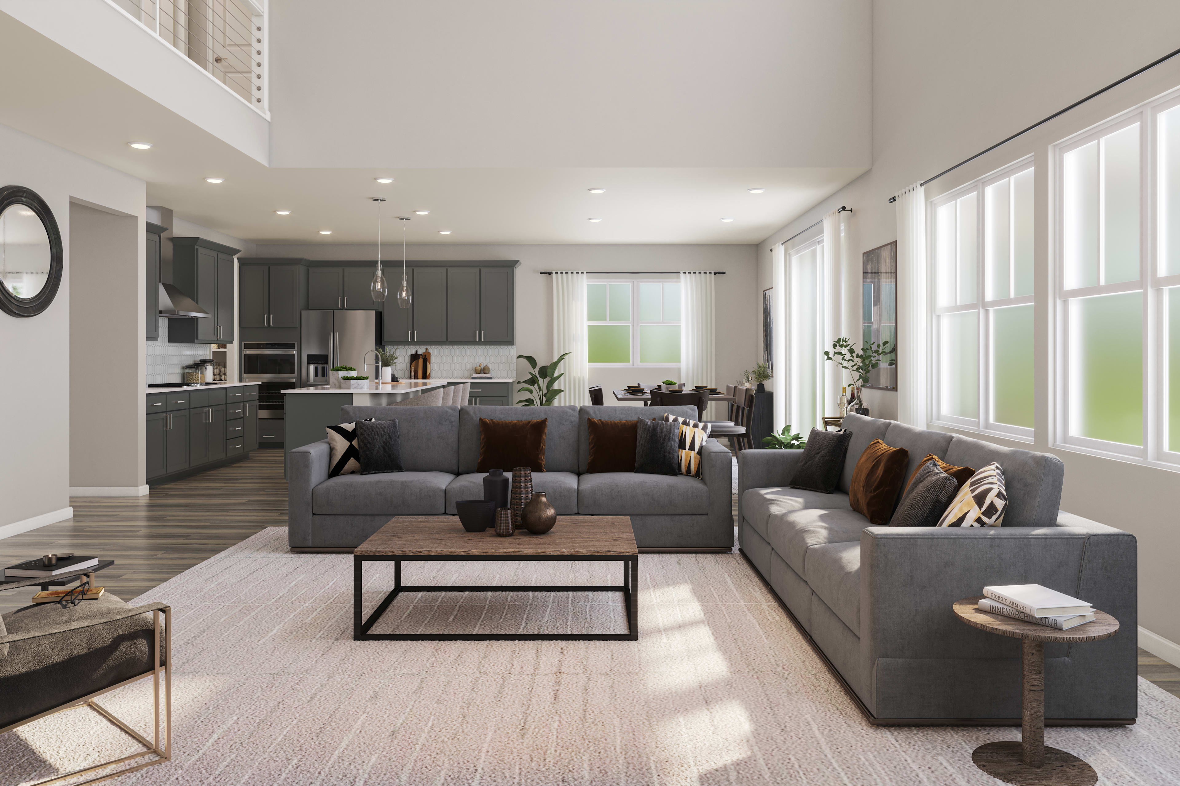 A spacious and modern living room with a large gray sectional sofa, a wooden coffee table, and a kitchen visible in the background with dark cabinets and stainless steel appliances.