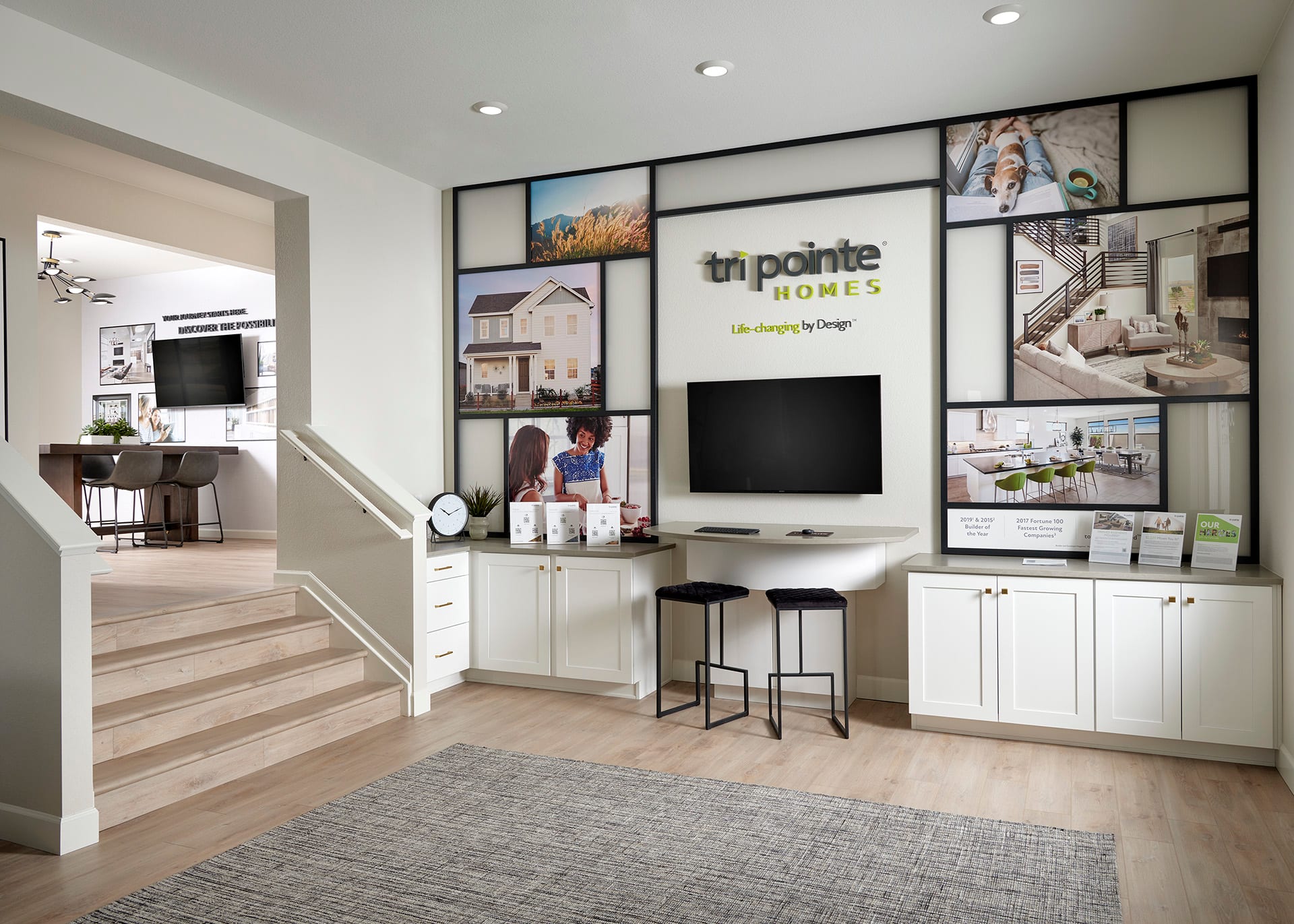 A modern and well-designed home interior with a TV display area, cabinets, and a staircase leading to another room.